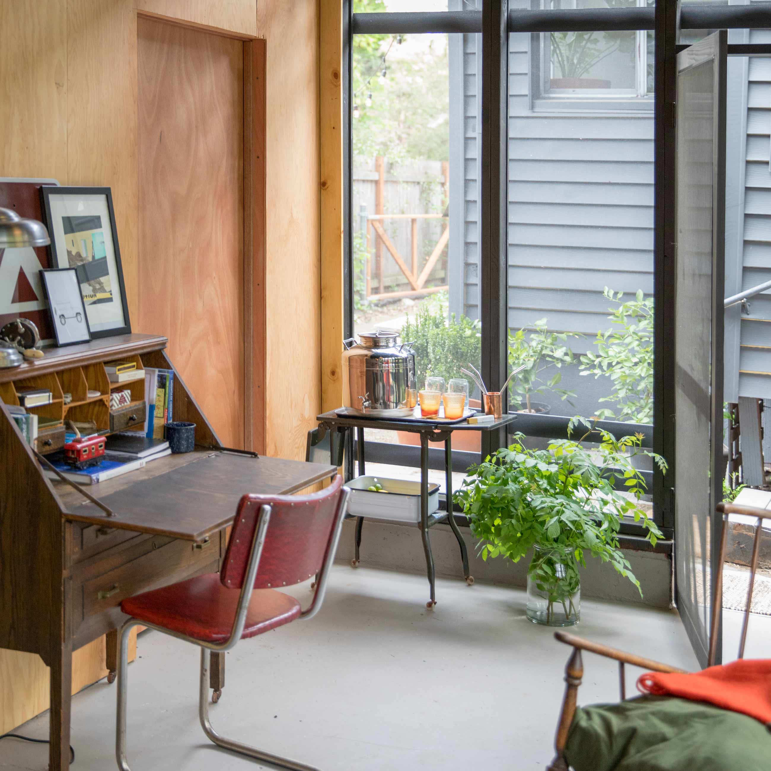 Small nook in the corner of the living room by a large window with a desk and plant.