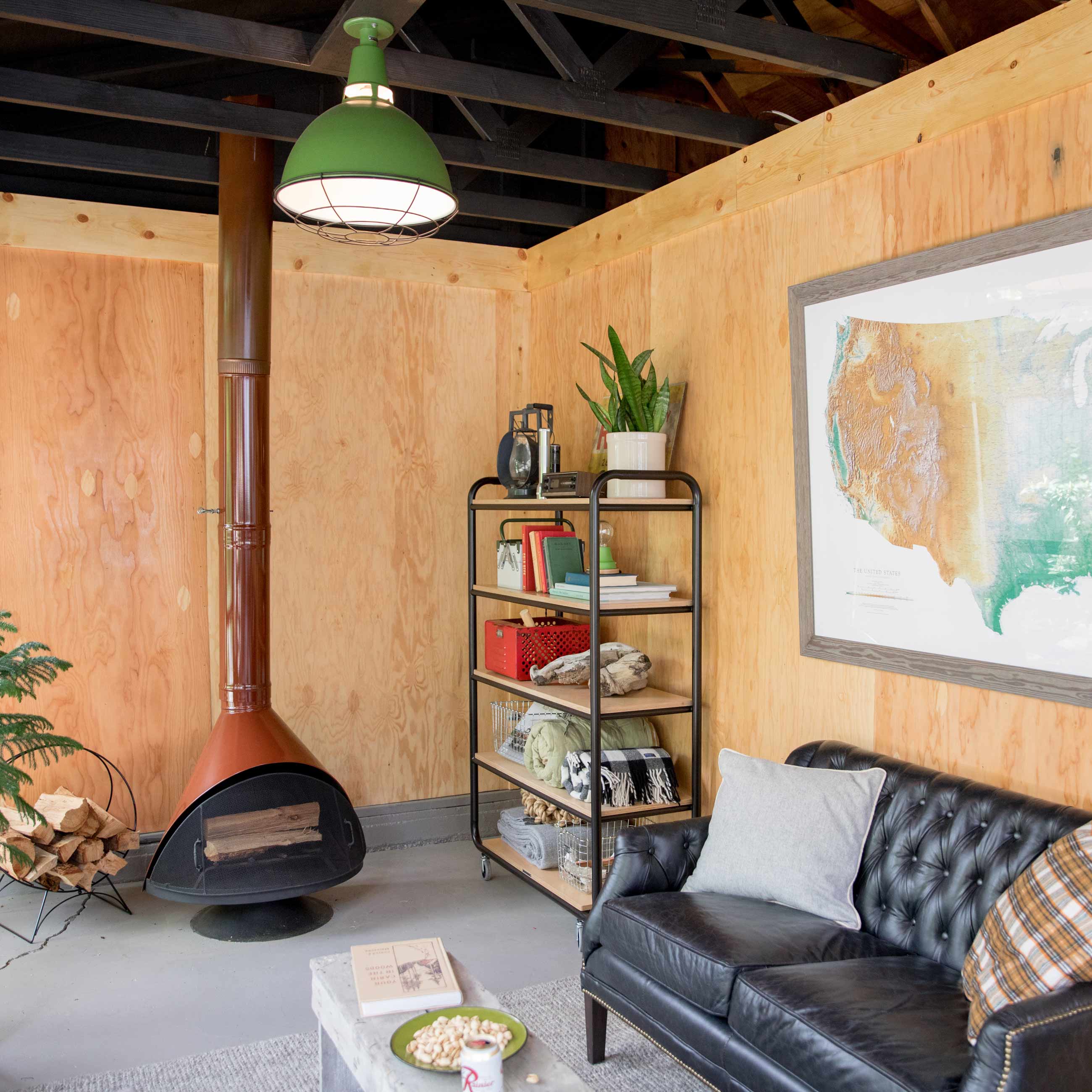 Rustic and industrial living space with a mid century fireplace, oak walls, and a green factory light overhead. 