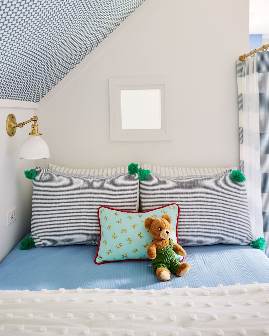 teddy bear sits on a bed with blue sheets 