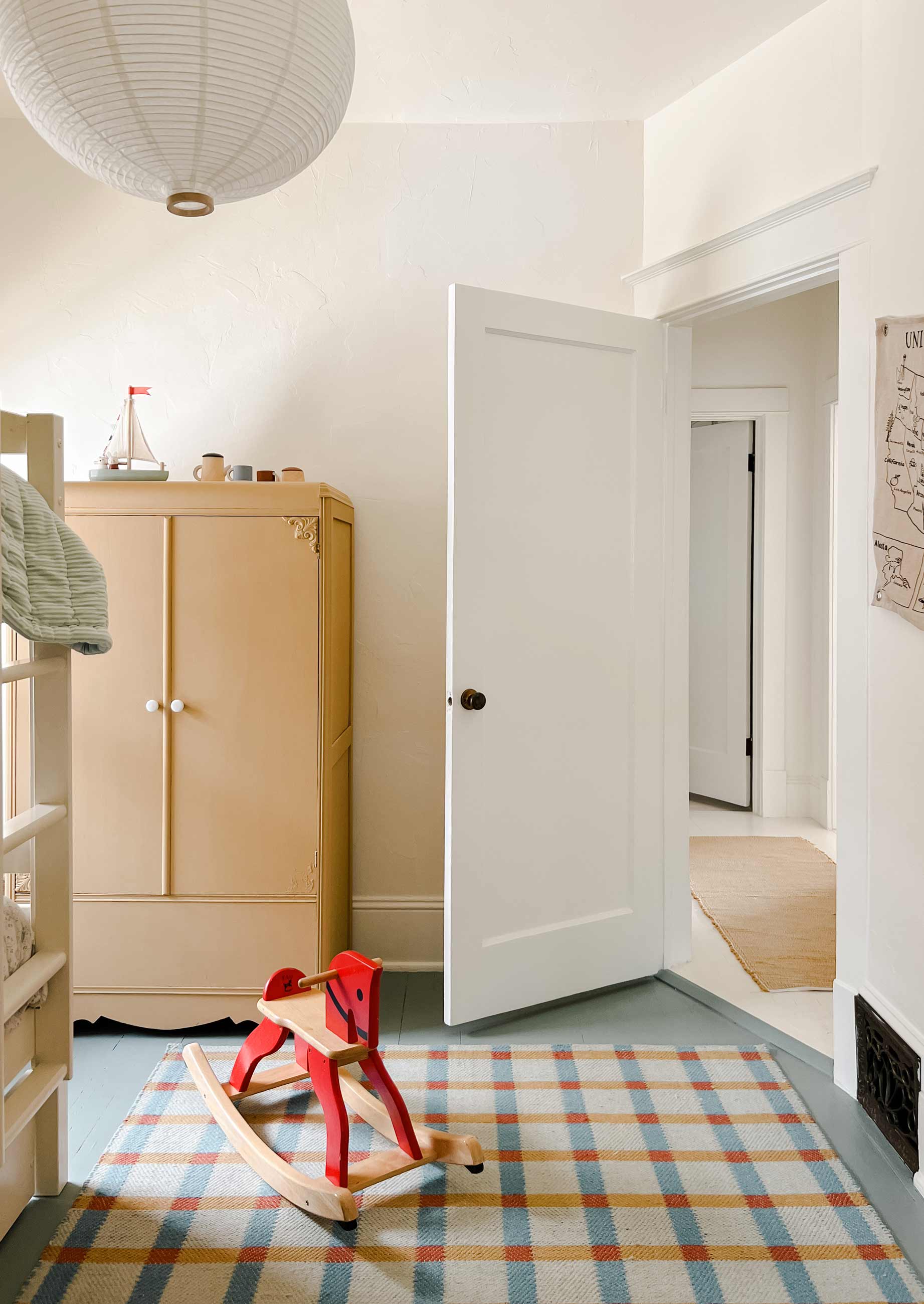 Kids bedroom with yellow armoire and plaid wool rug. 