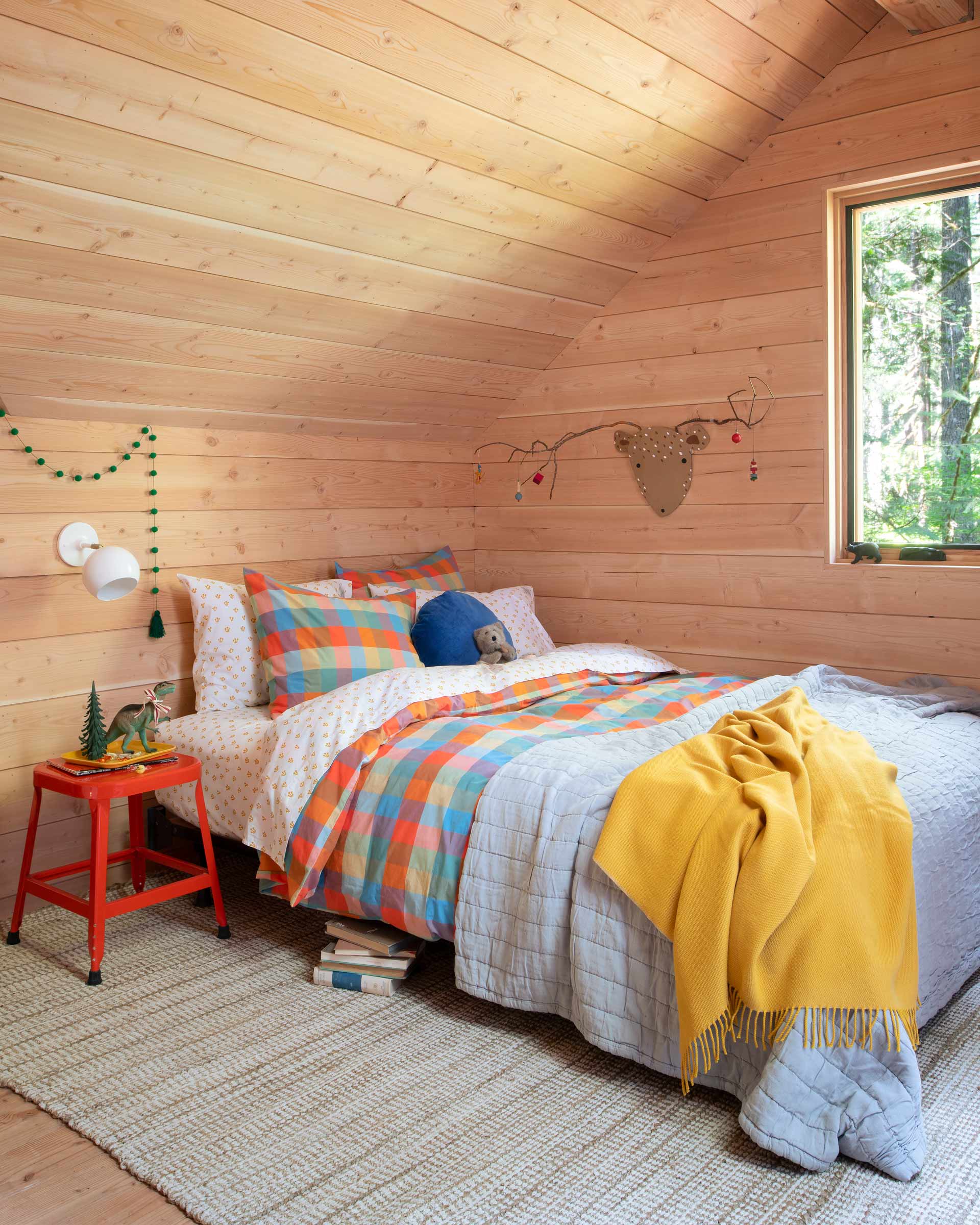 Kid's bedroom in a cabin loft with holiday decor and playful bedding.