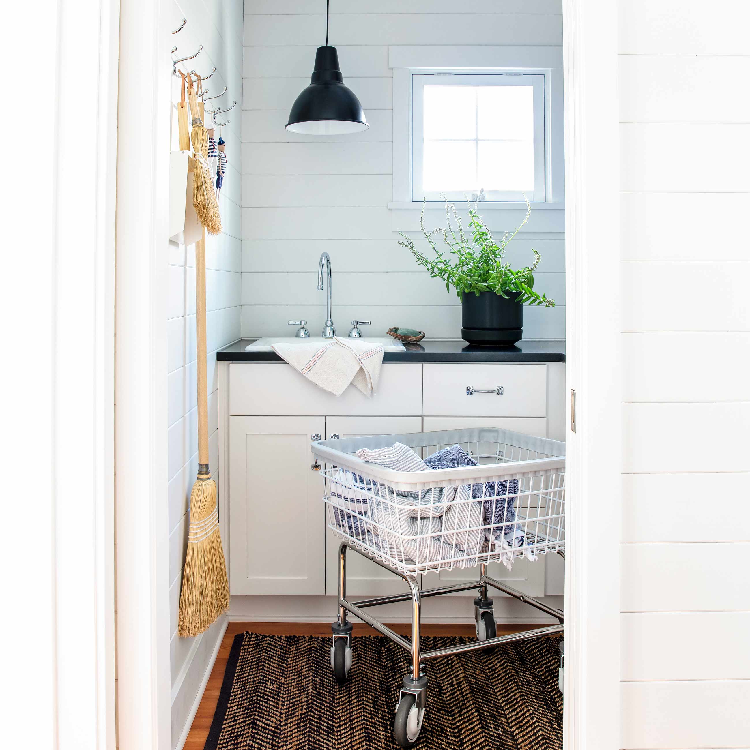 Clean laundry room with laundry cart and black factory pendant. 