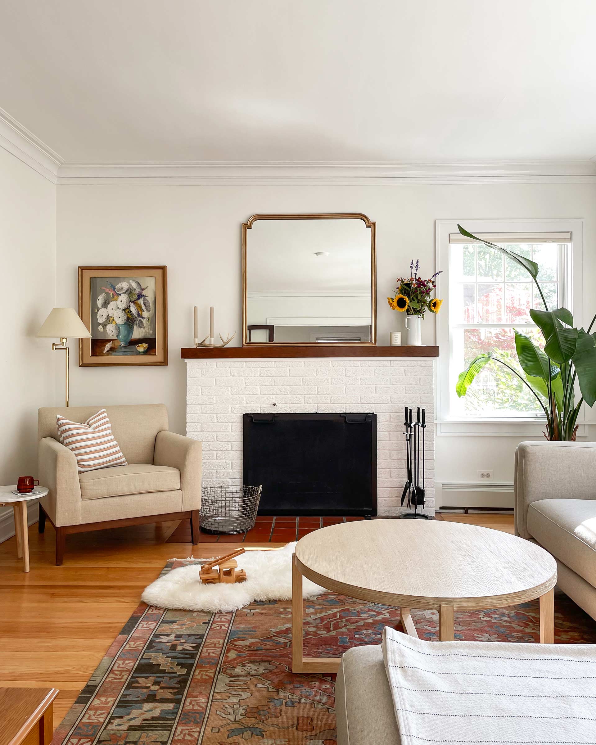 Living room with a white, brick fireplace and heirloom home decor.