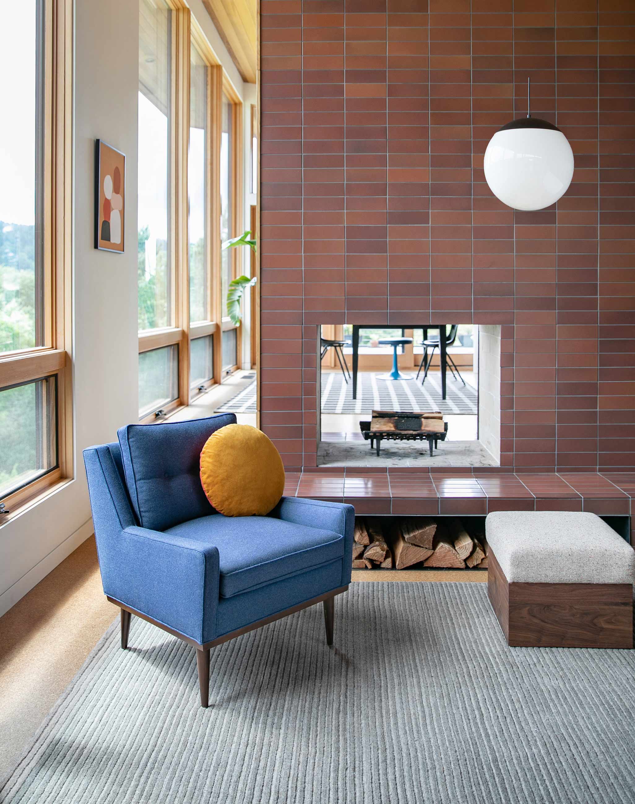 Mid century style chair next to open fireplace with globe bulb light fixture hanging above.