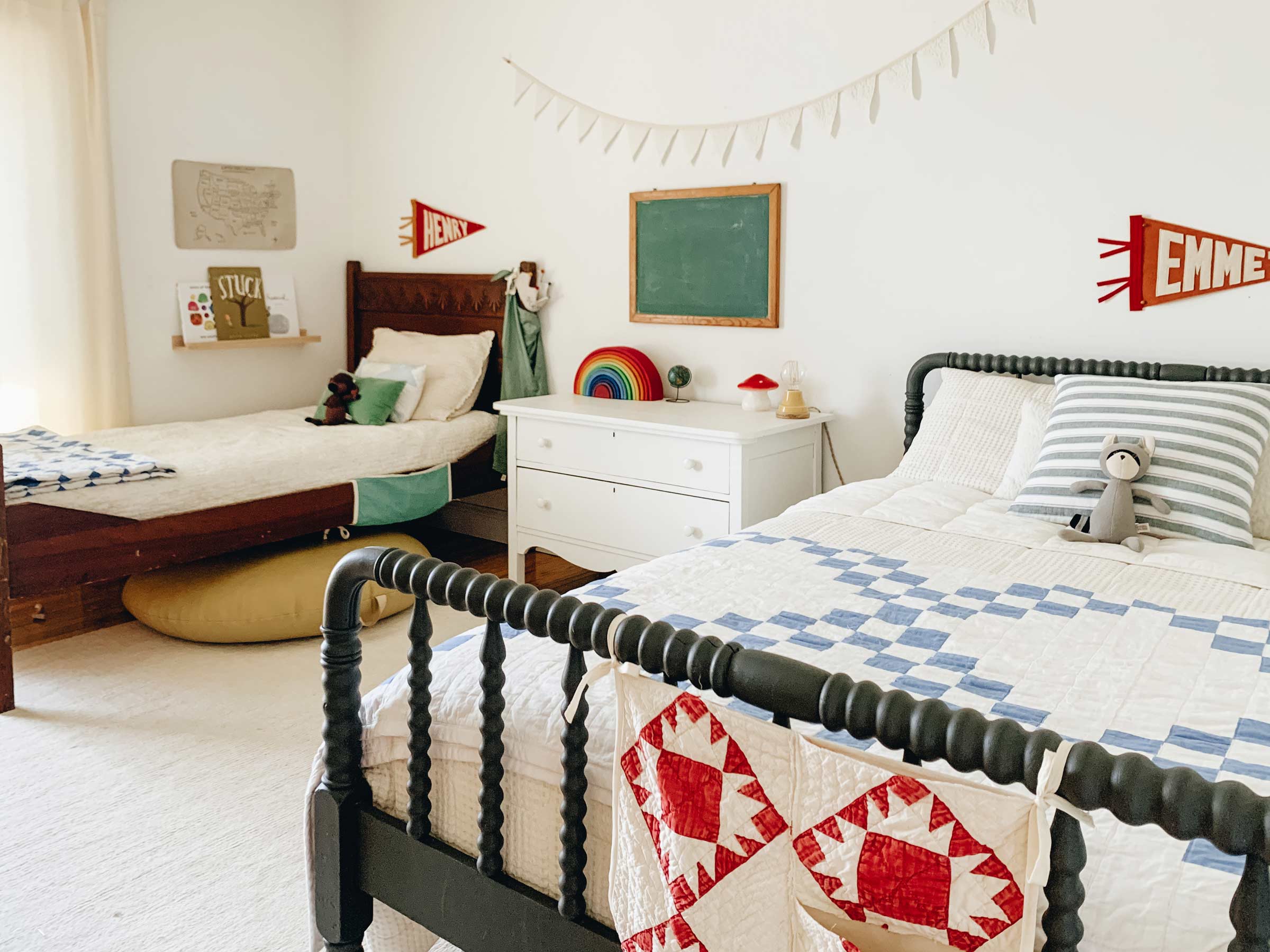 A kid's room with two beds and vintage bedding. 