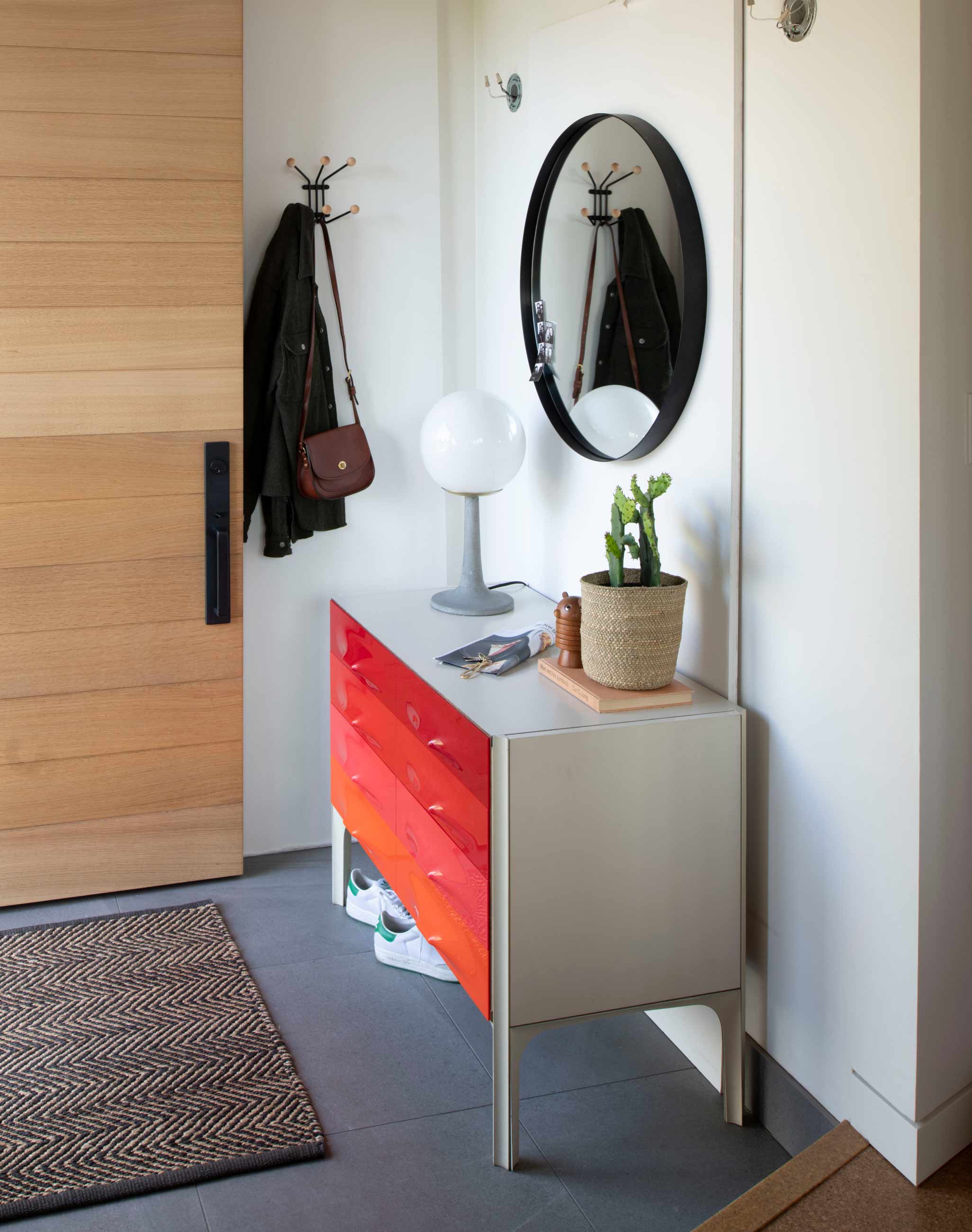 Modern entryway with red credenza and modern, concrete lamp.