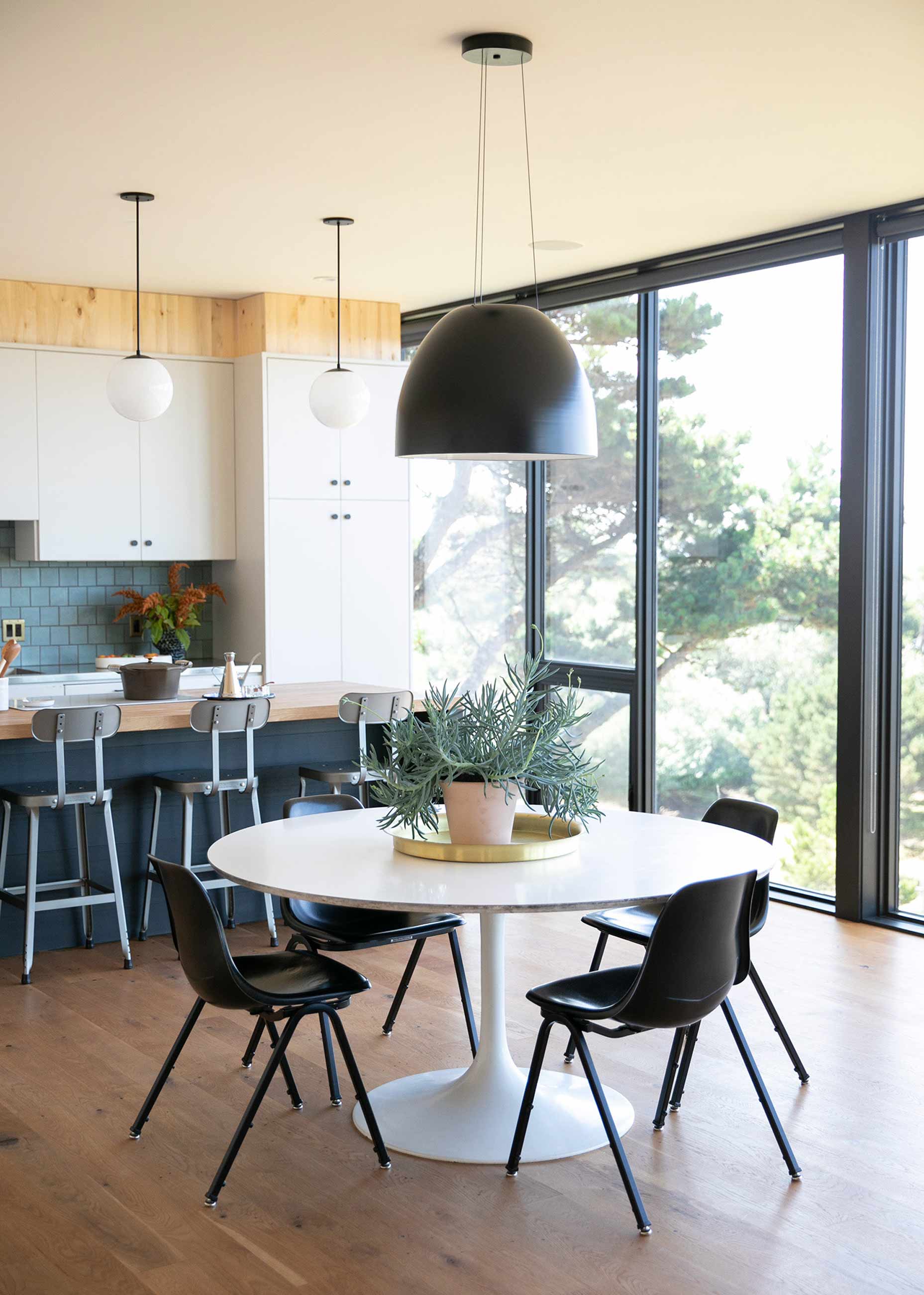 Modern open kitchen with wood floor and small tulip dining table in front of island.