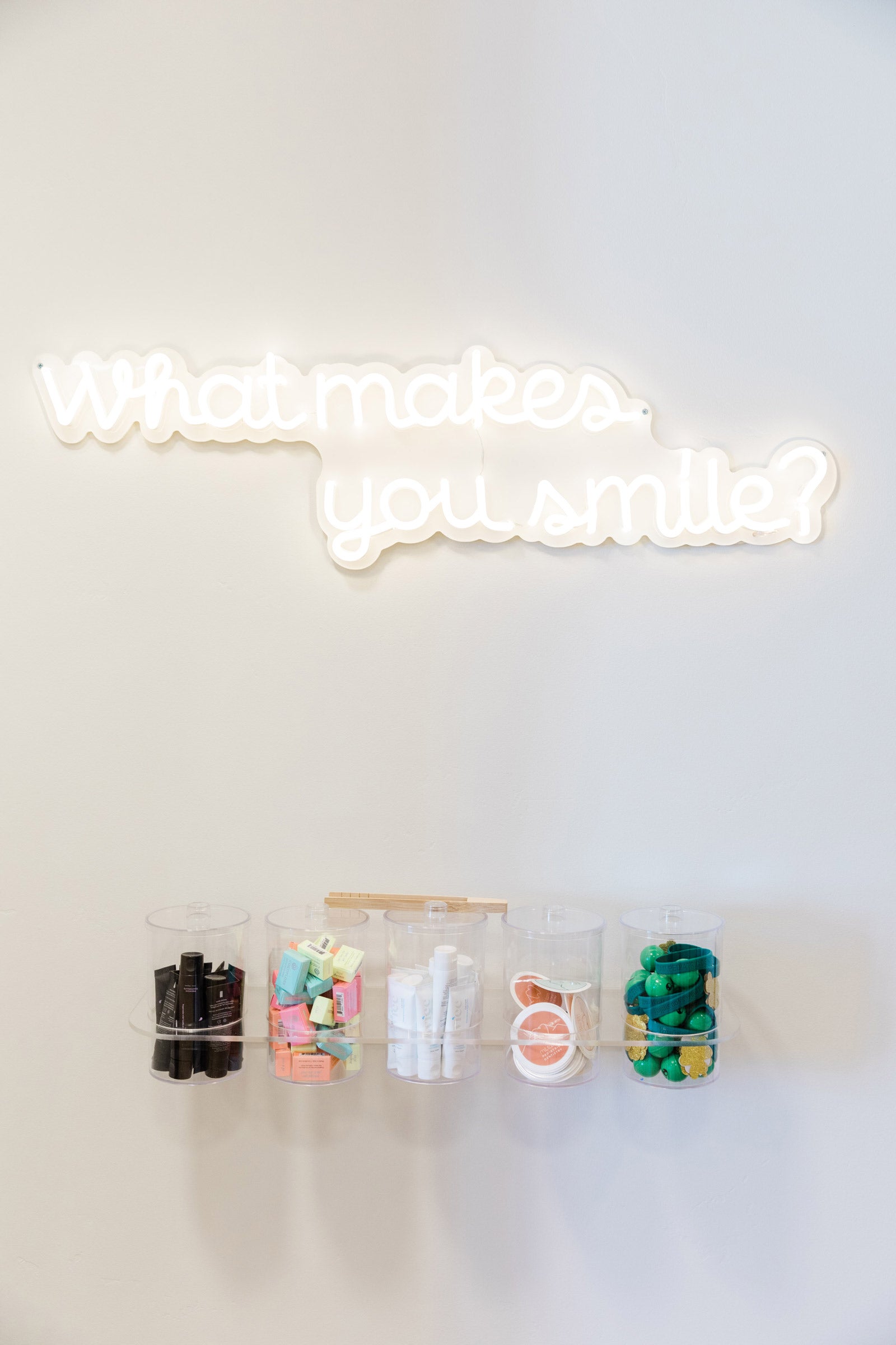 A neon sign that says "what makes you smile?" at a pediatric dental office.