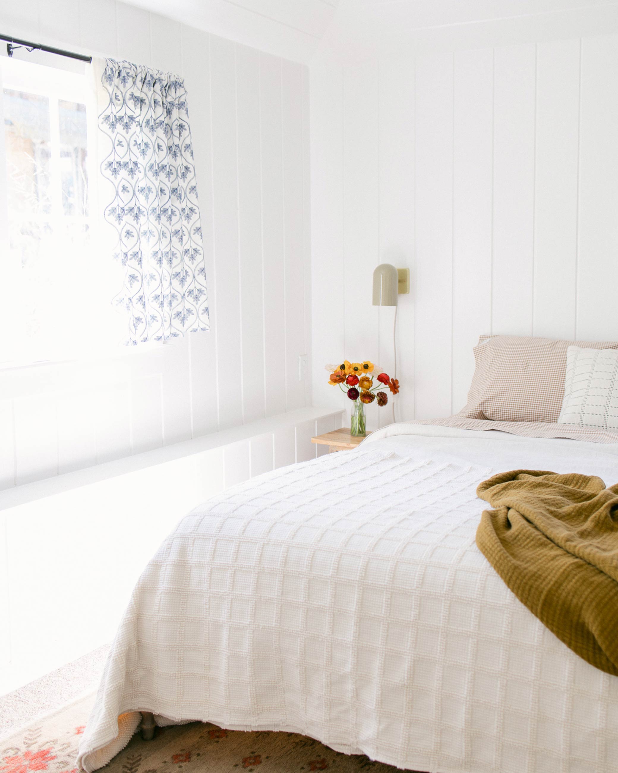 Ivory cotton quilt with gingham pillowcases in a bright bedroom. 