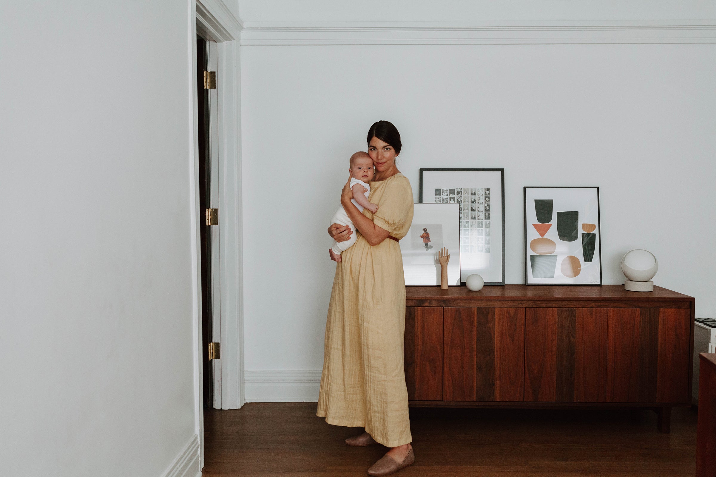 person in a yellow dress holding an infant