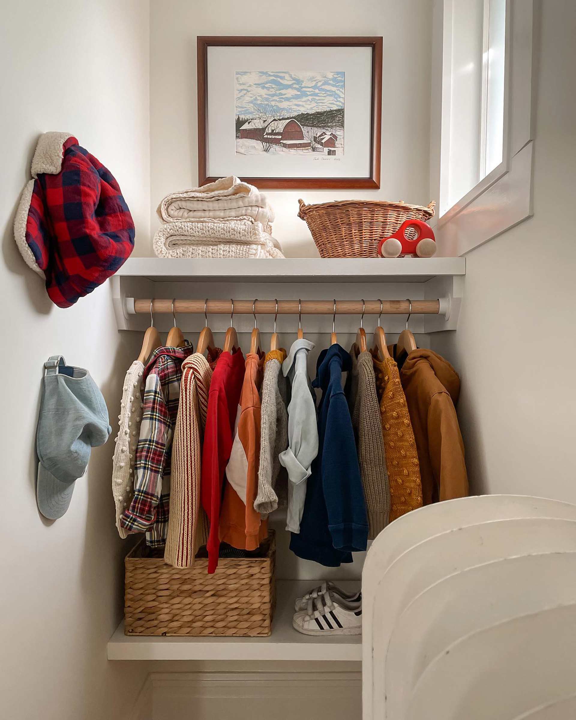 A well-organized kid's closet nook in a small room with a window.