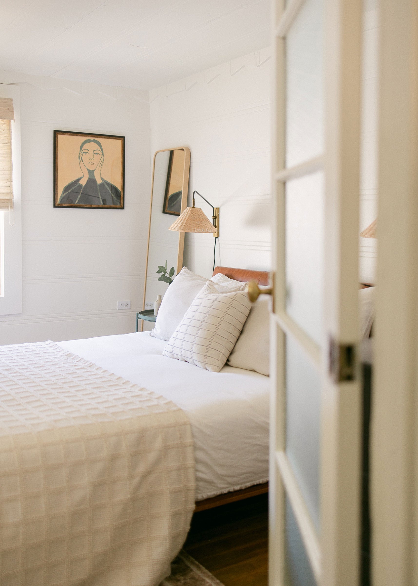 Door slightly ajar looking into a cozy bedroom styled with a neutral cotton quilt.