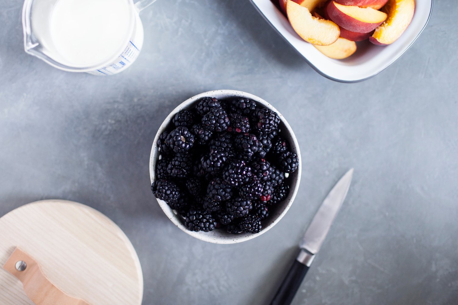 bowl of blackberries and a bowl of sliced peaches on a table
