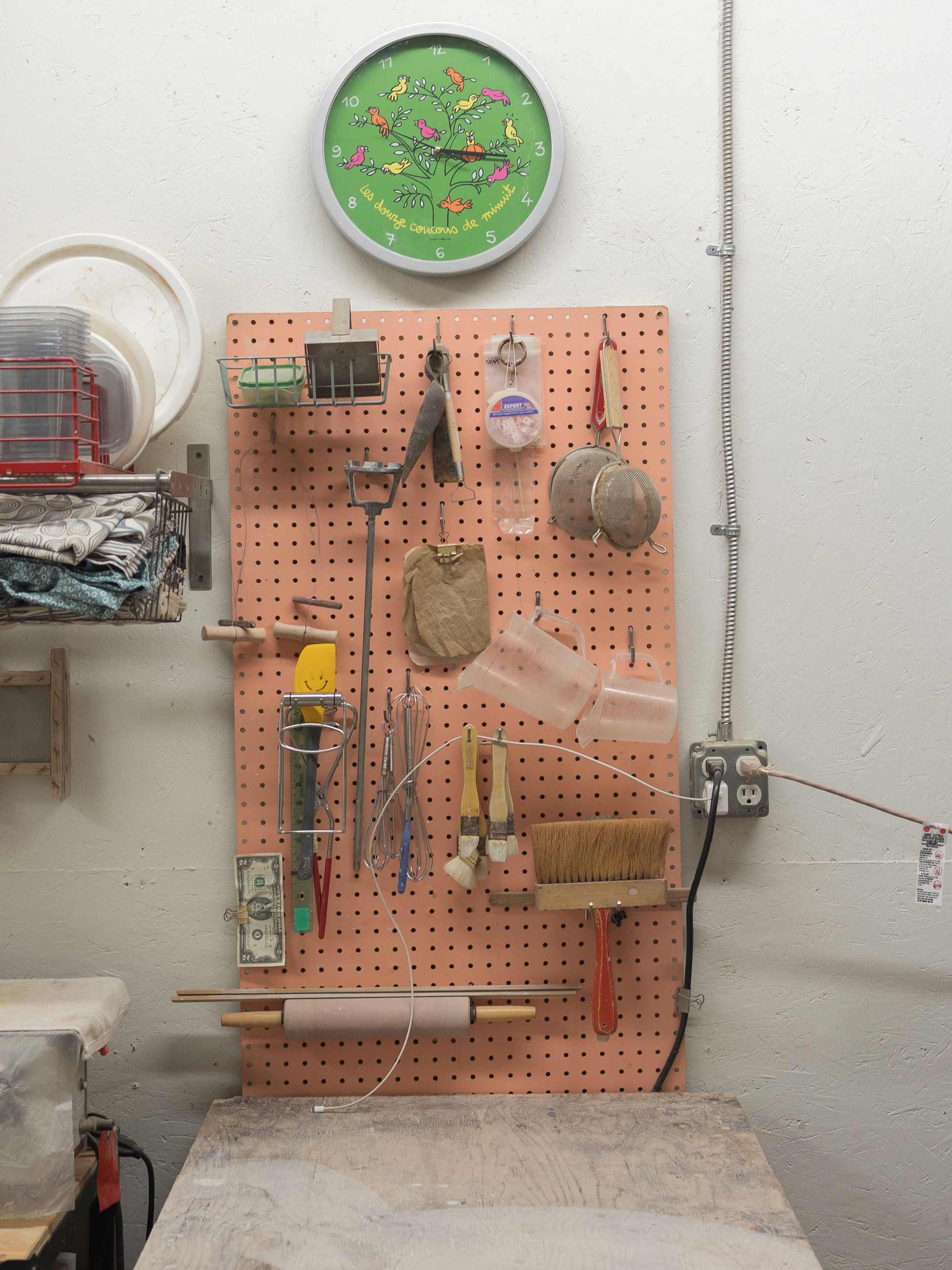 Pink pegboard with green clock above.