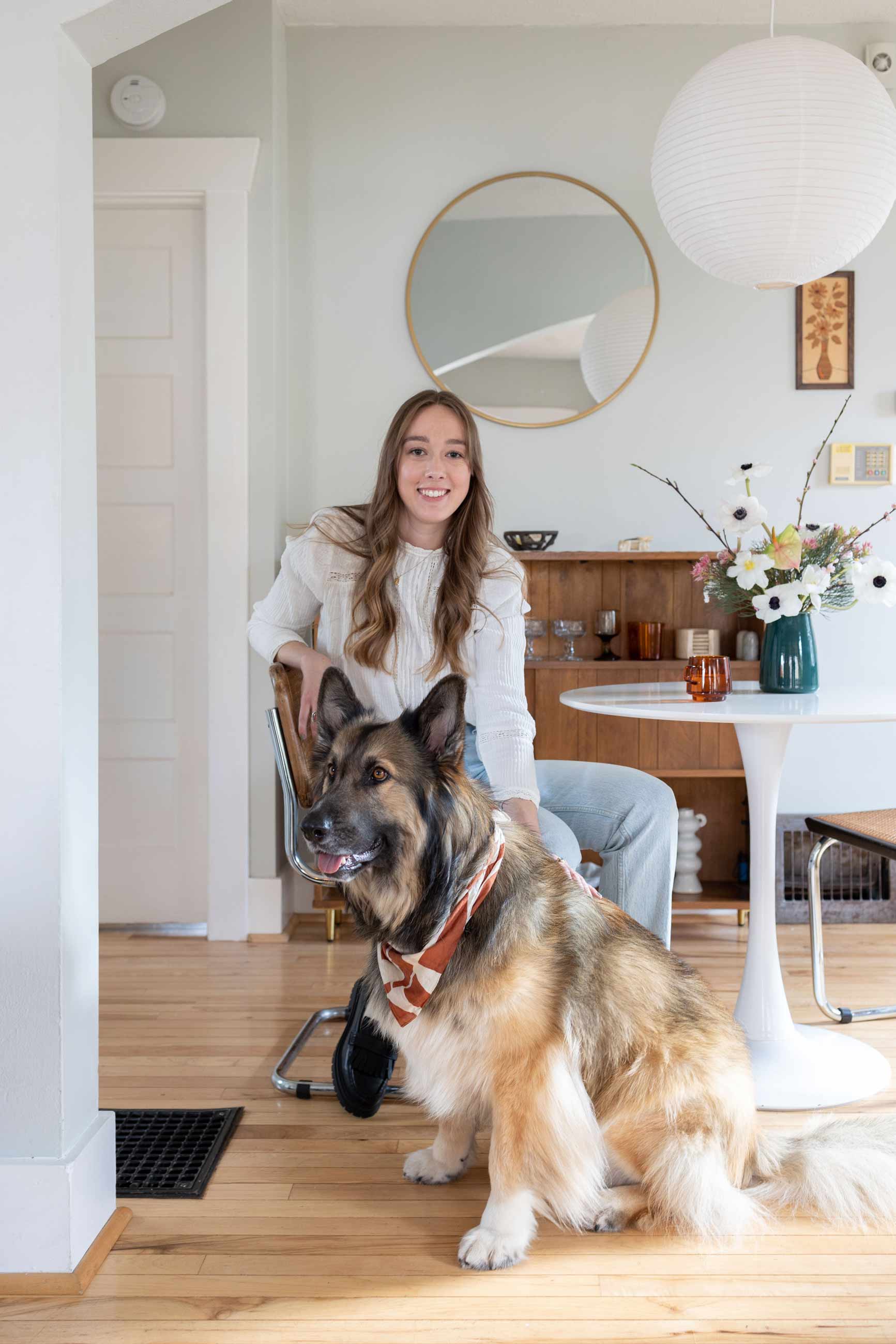 Person sitting at tulip table in dining room with dog at their side. 