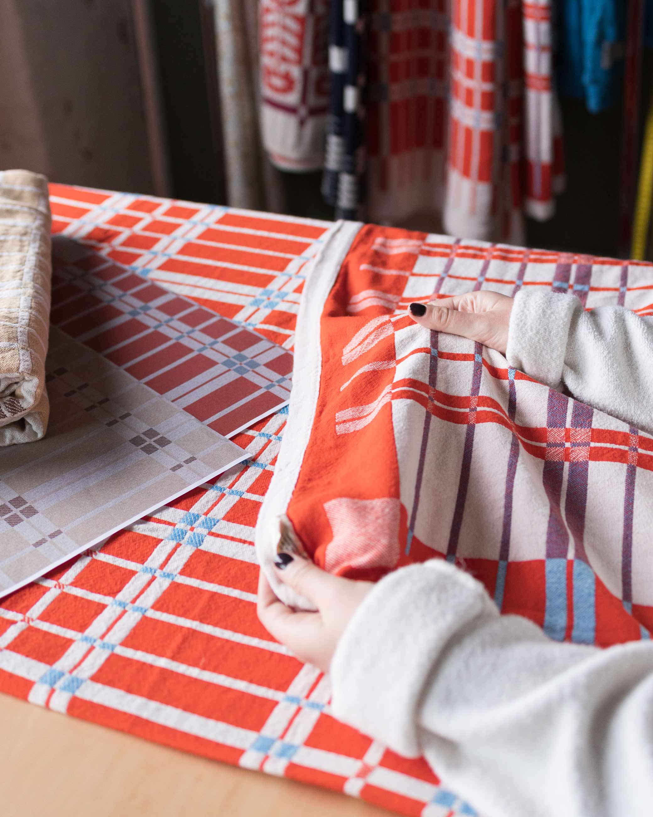 Person holding cotton coverlet to assess quality. 