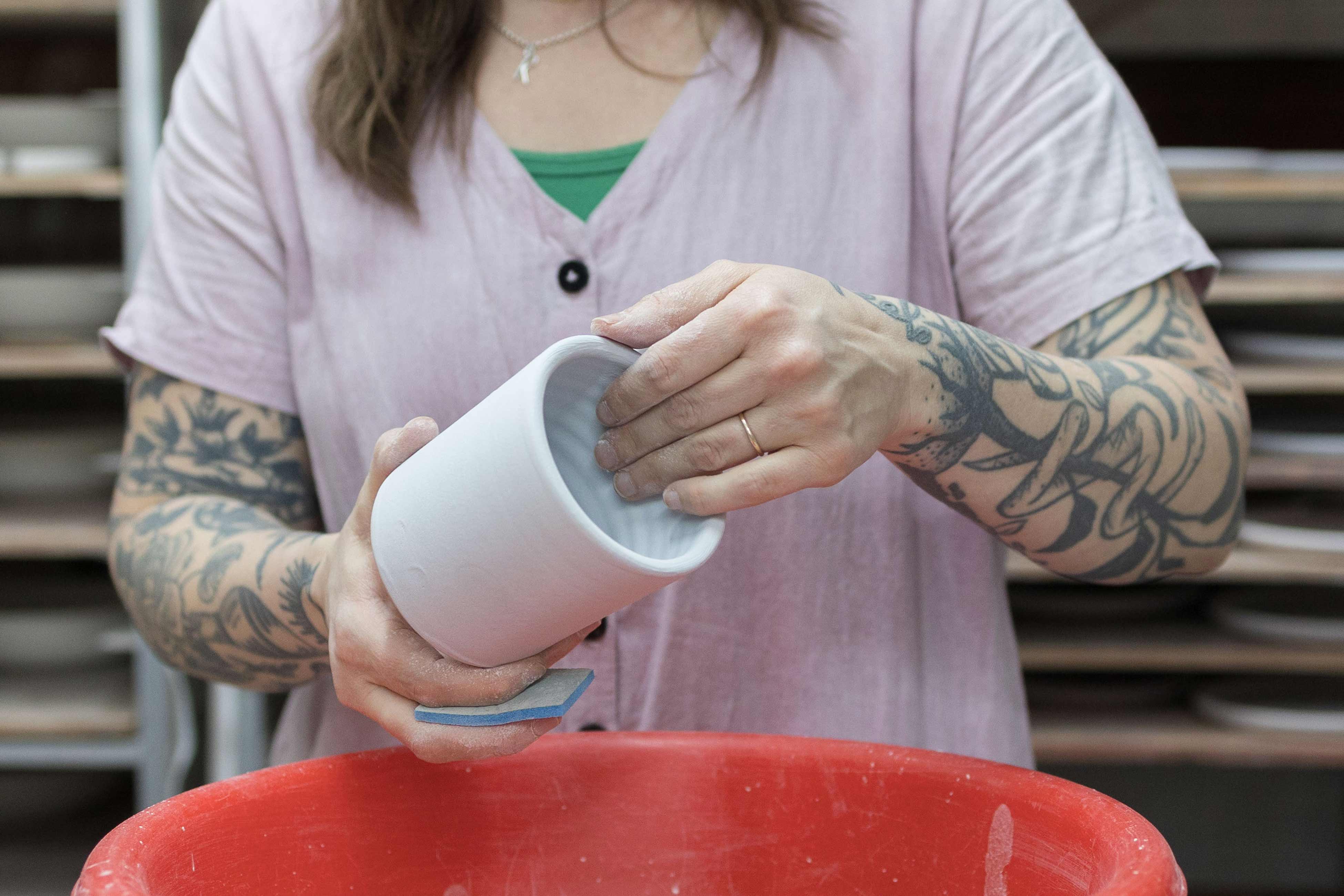 Person sanding down ceramic vase after it came out of the kiln.