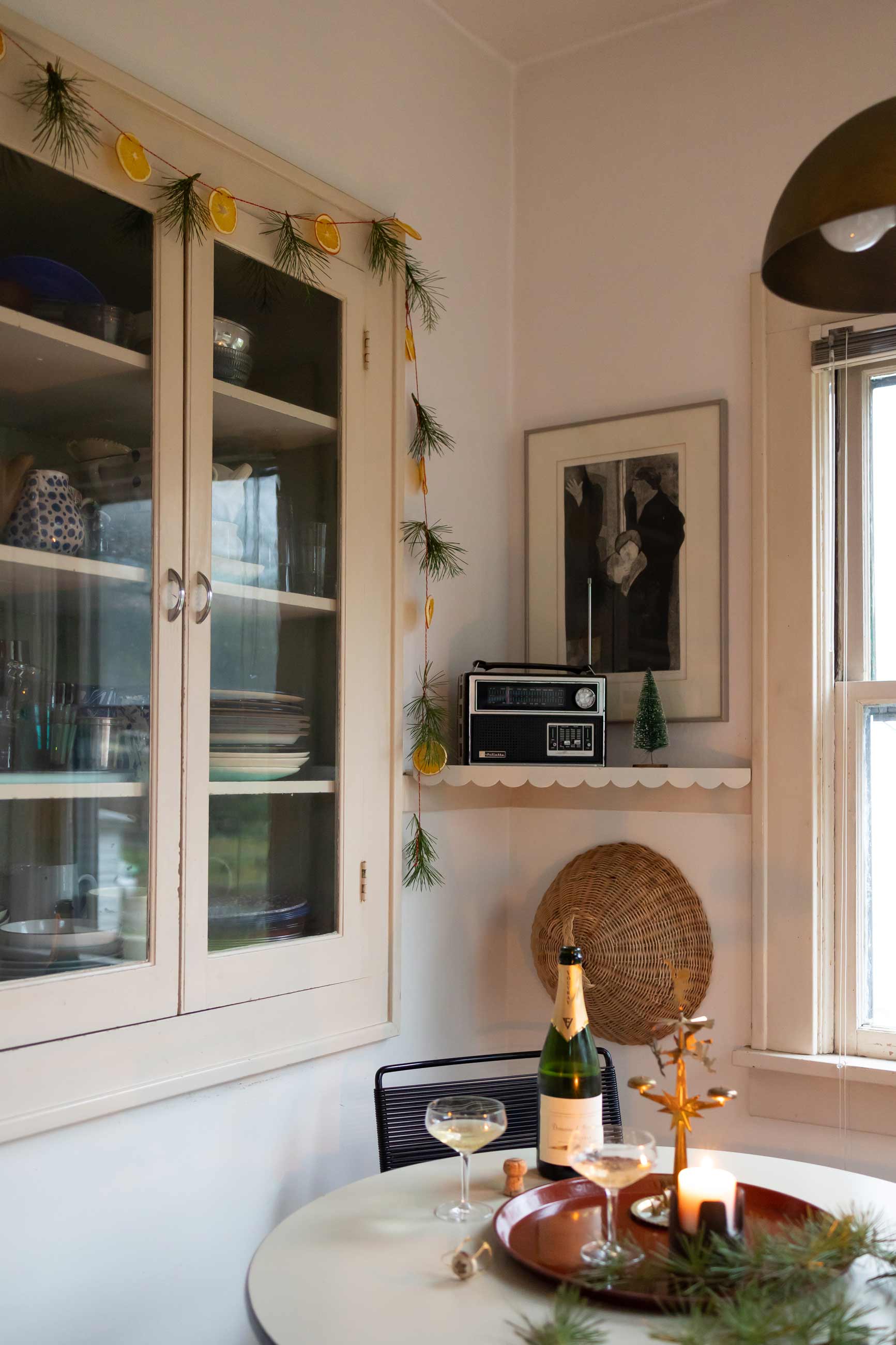 Pine and dried citrus garland hanging on built-in cabinet in front of kitchen table.