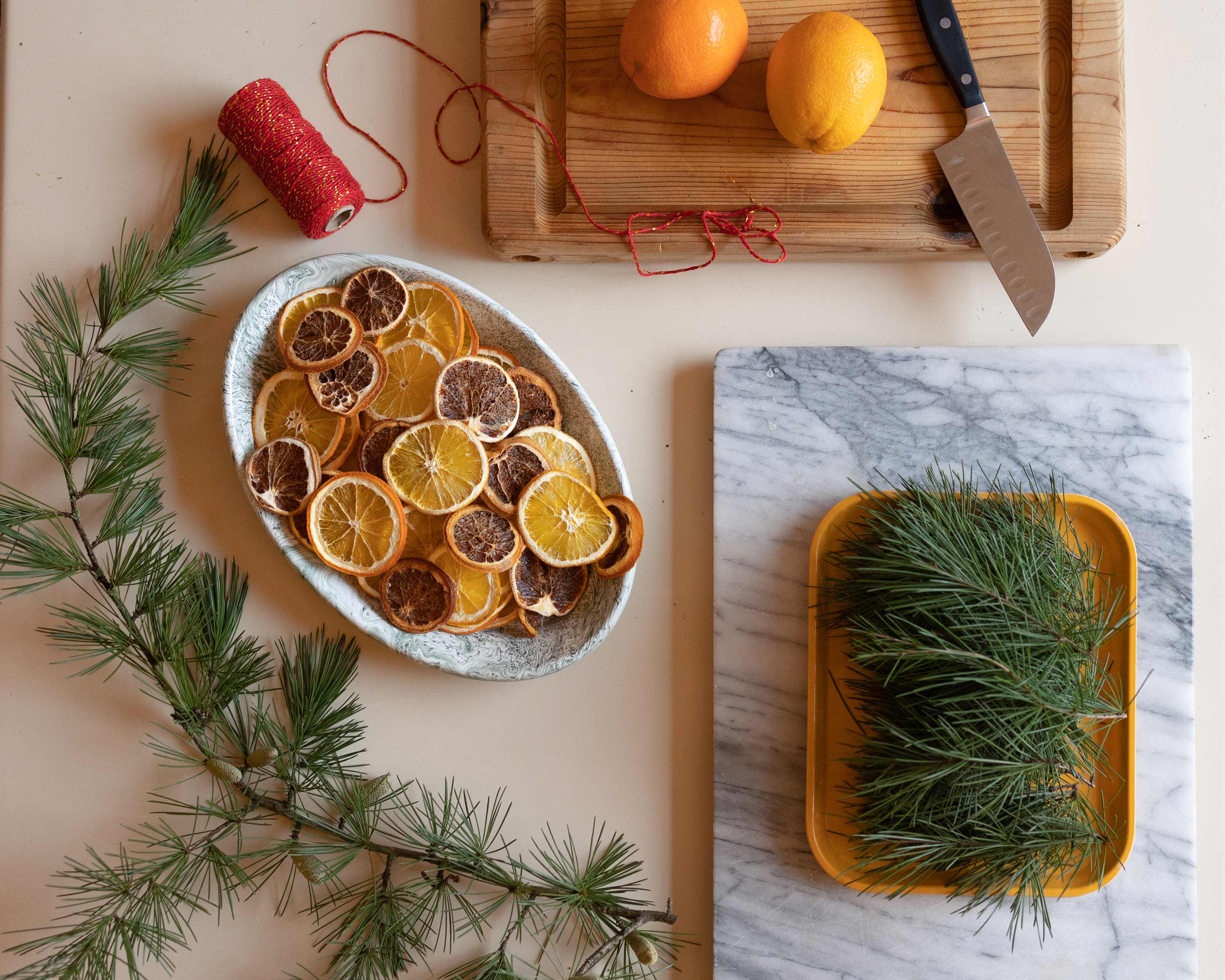 Pine needles and dried citrus on table with twine.