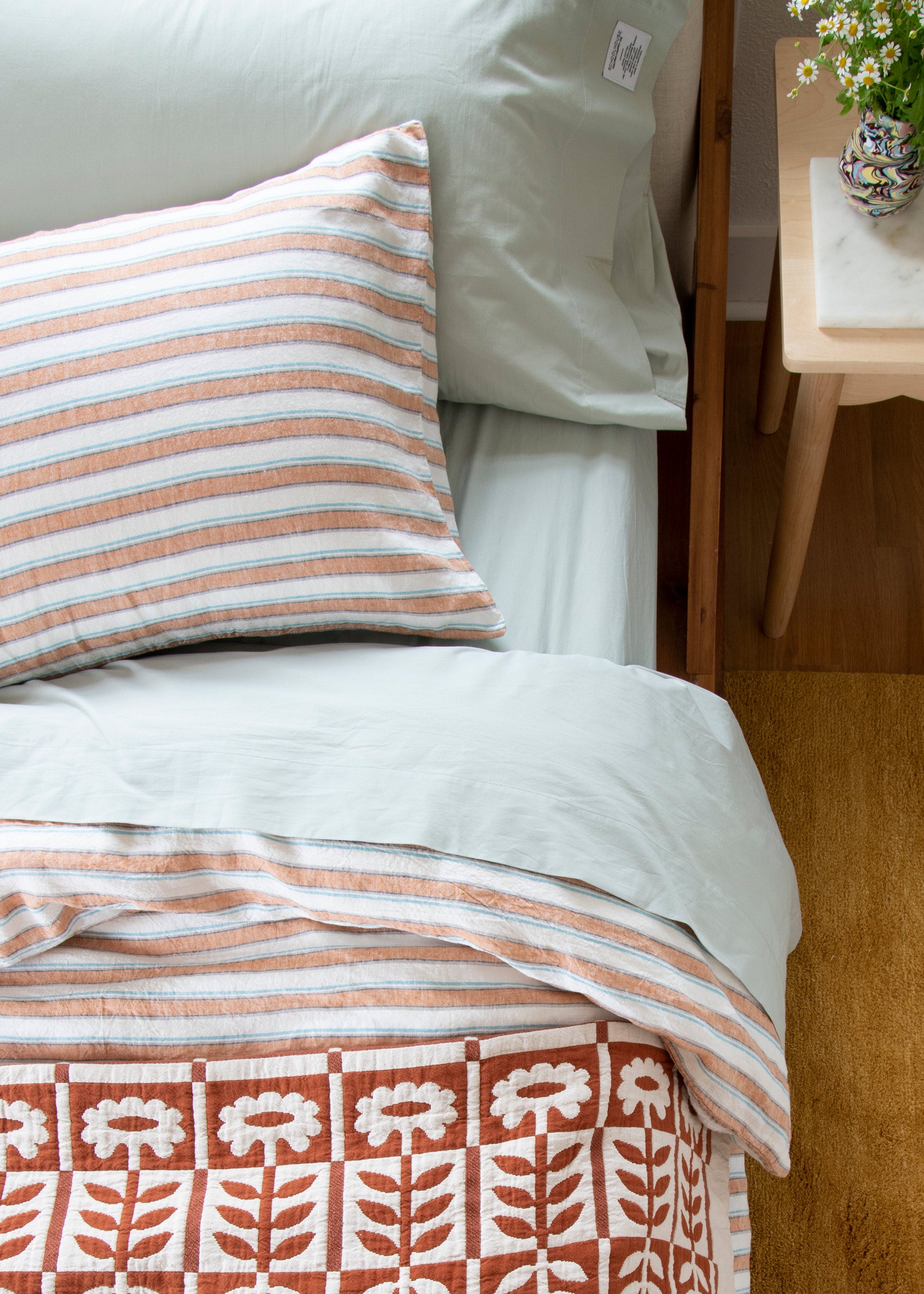 Close up shot of bed with pink, red, and green bedding.