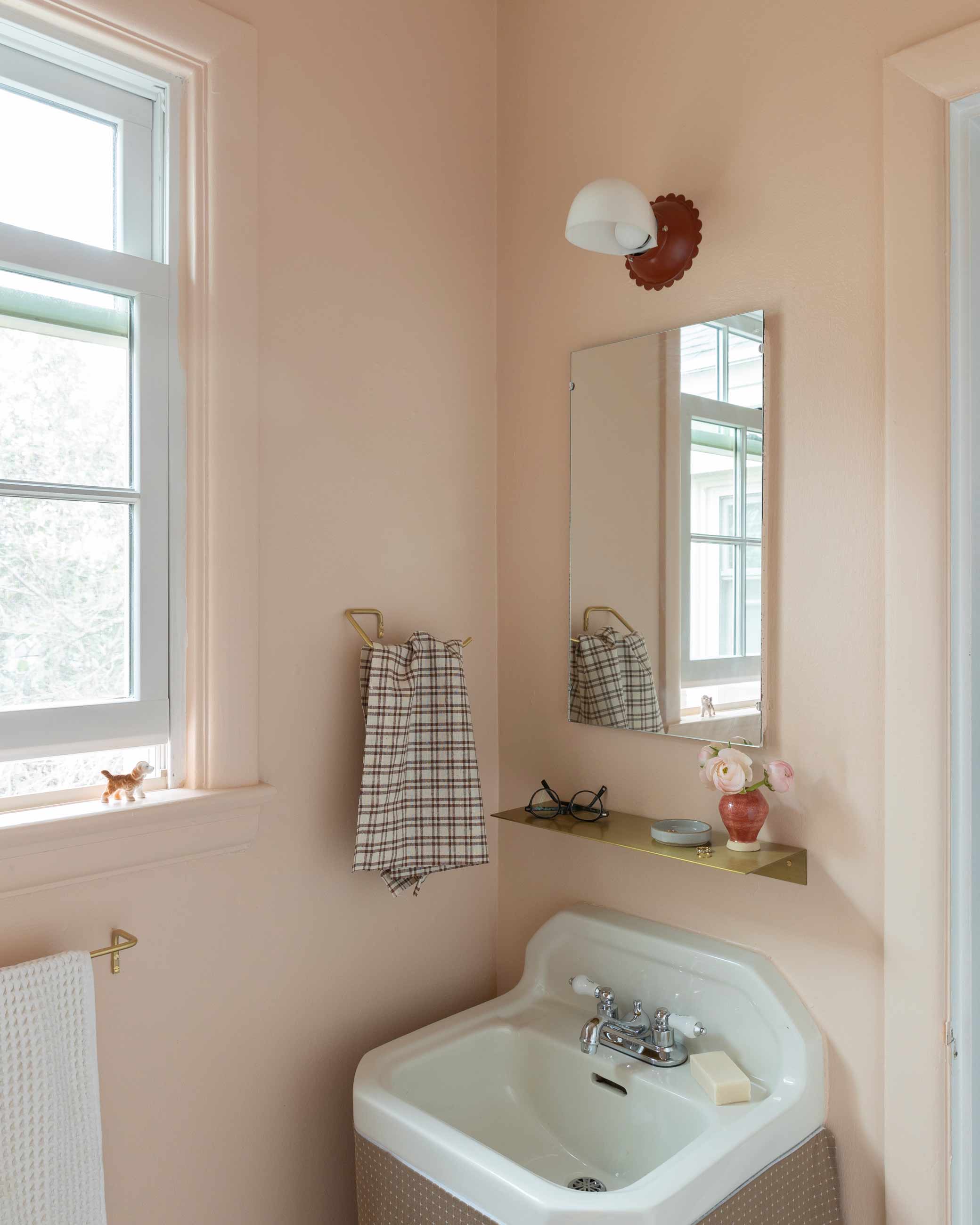 Pink bathroom with scalloped light over sink.