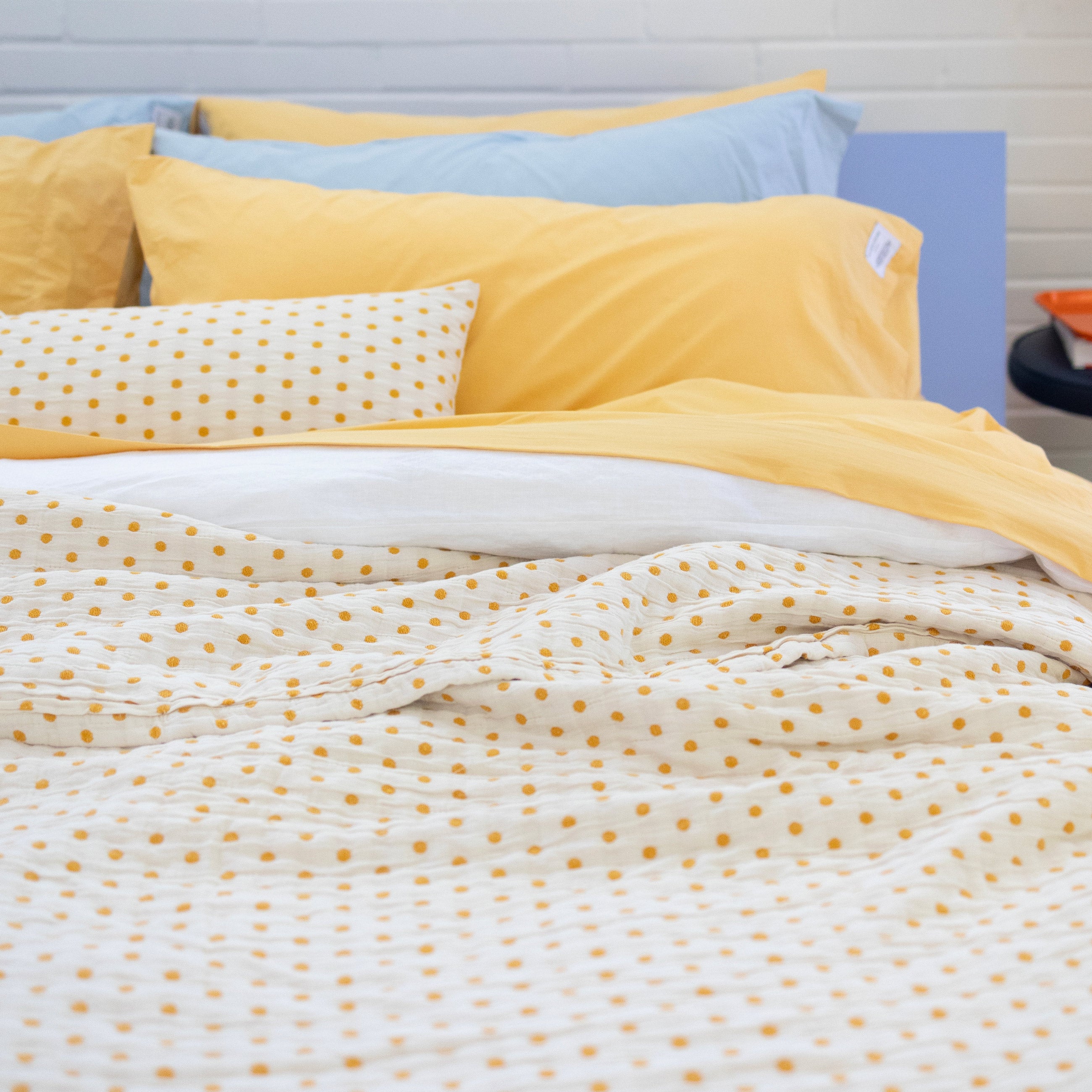 Yellow and white polka dot quilt on top of bed. 