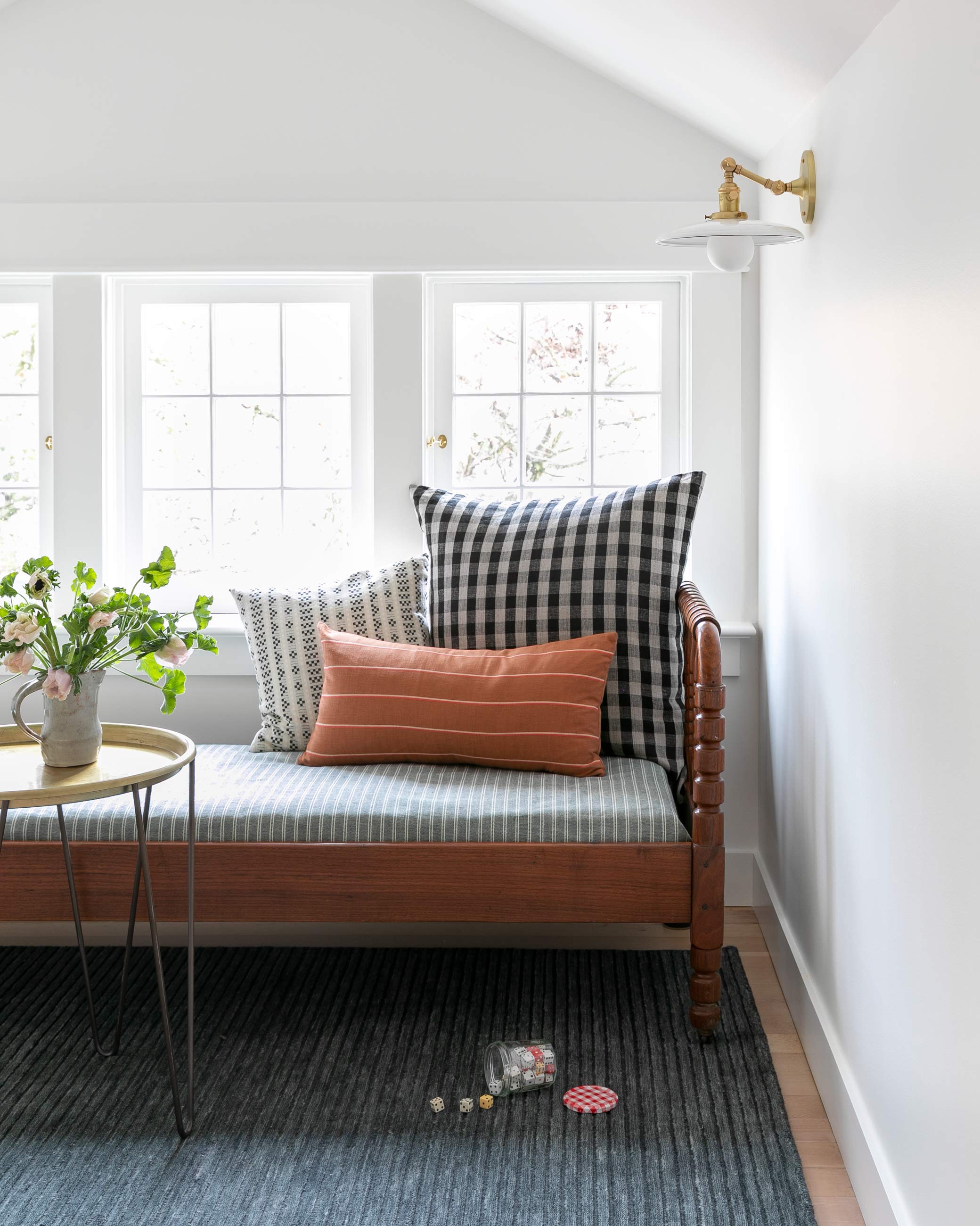 Cozy reading nook with bench, throw pillows, and a brass wall sconce.