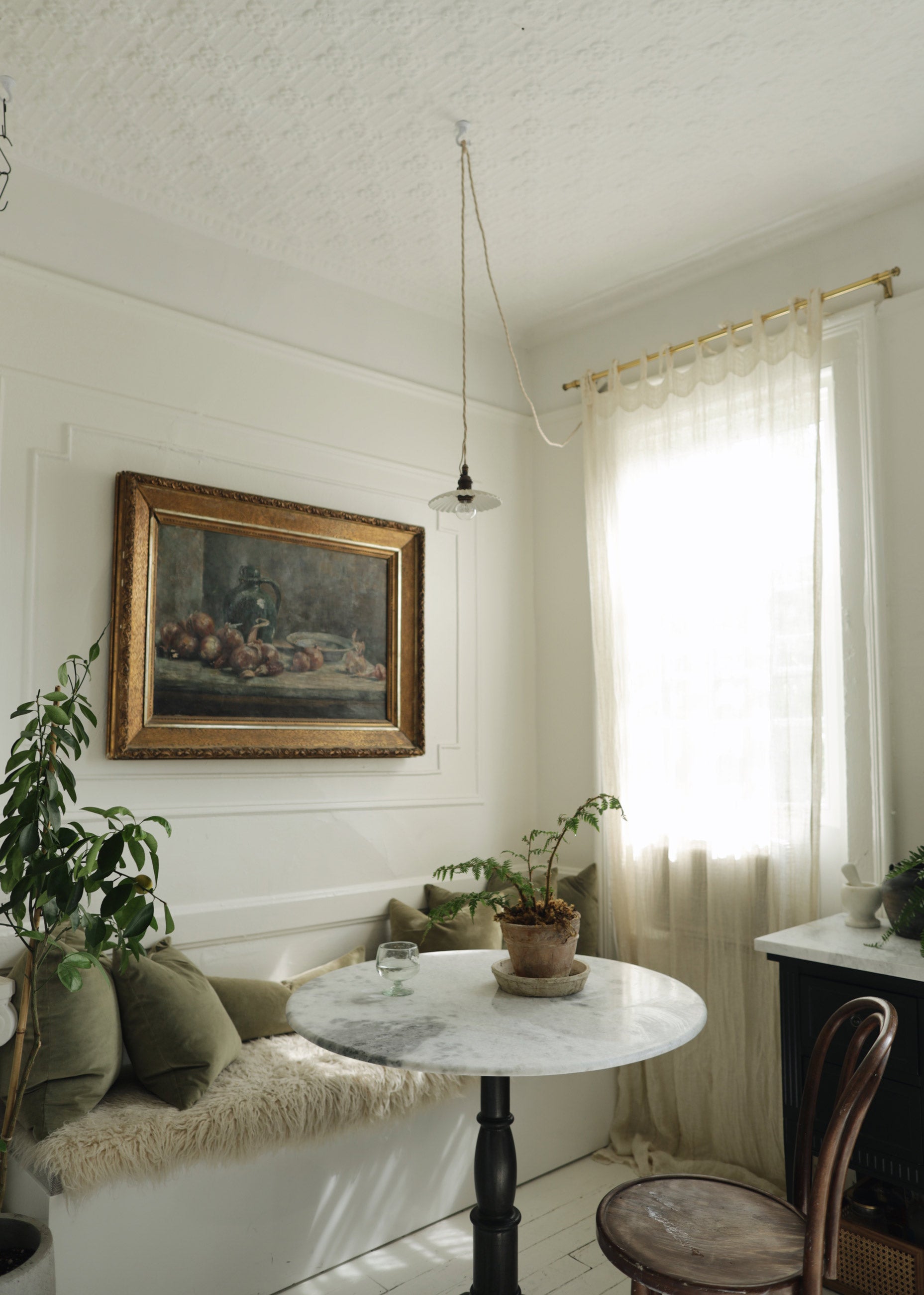 Romantic dining nook with plants and pillows.