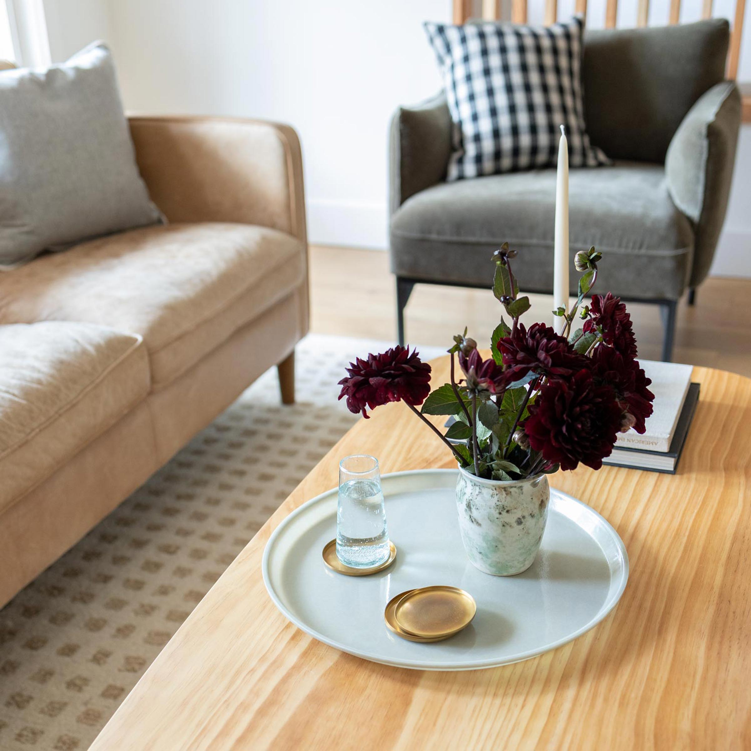 Round everyday, all-purpose tray with brass coasters and a floral arrangement on top.