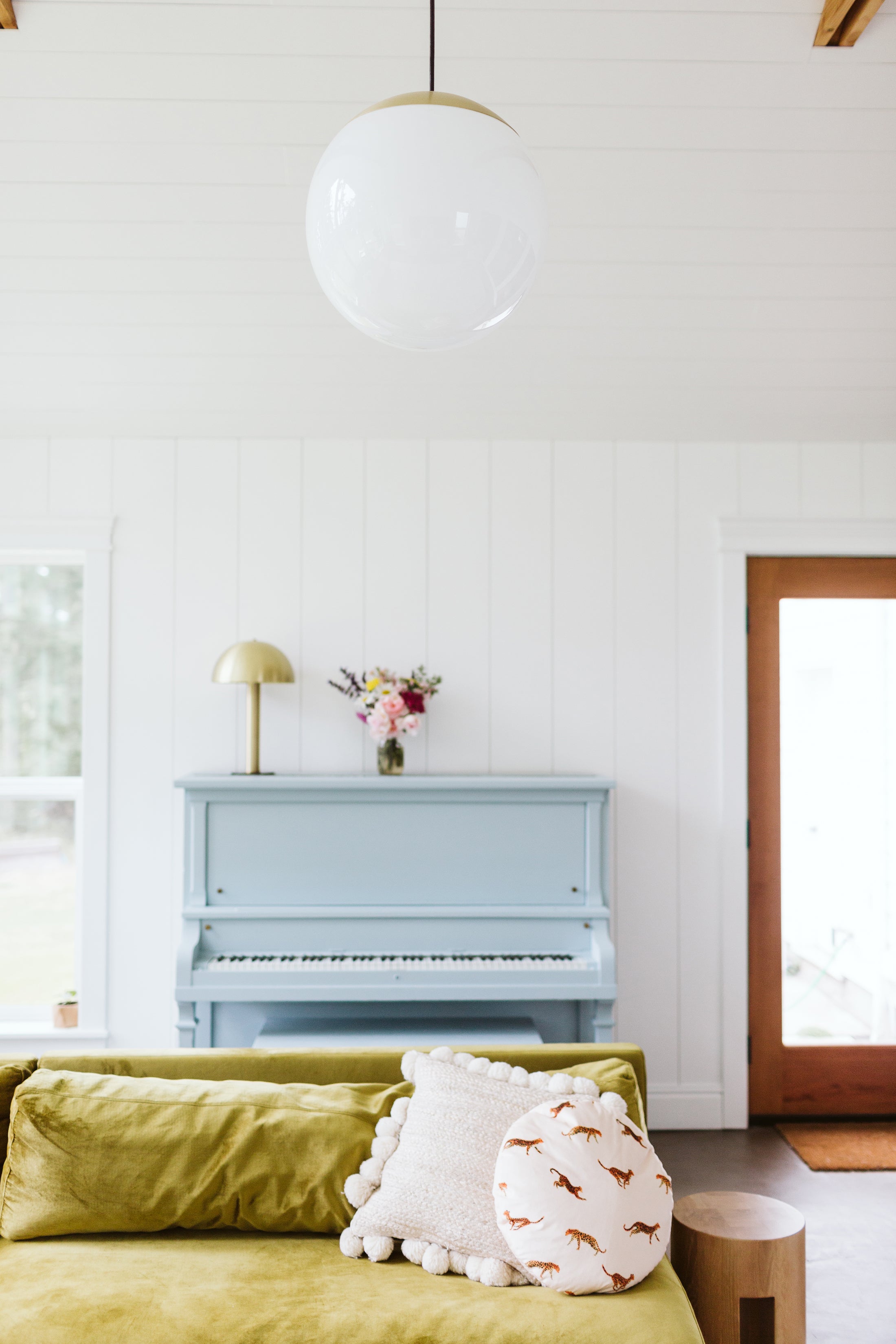 light blue piano in a livingroom with green couch and white pillows