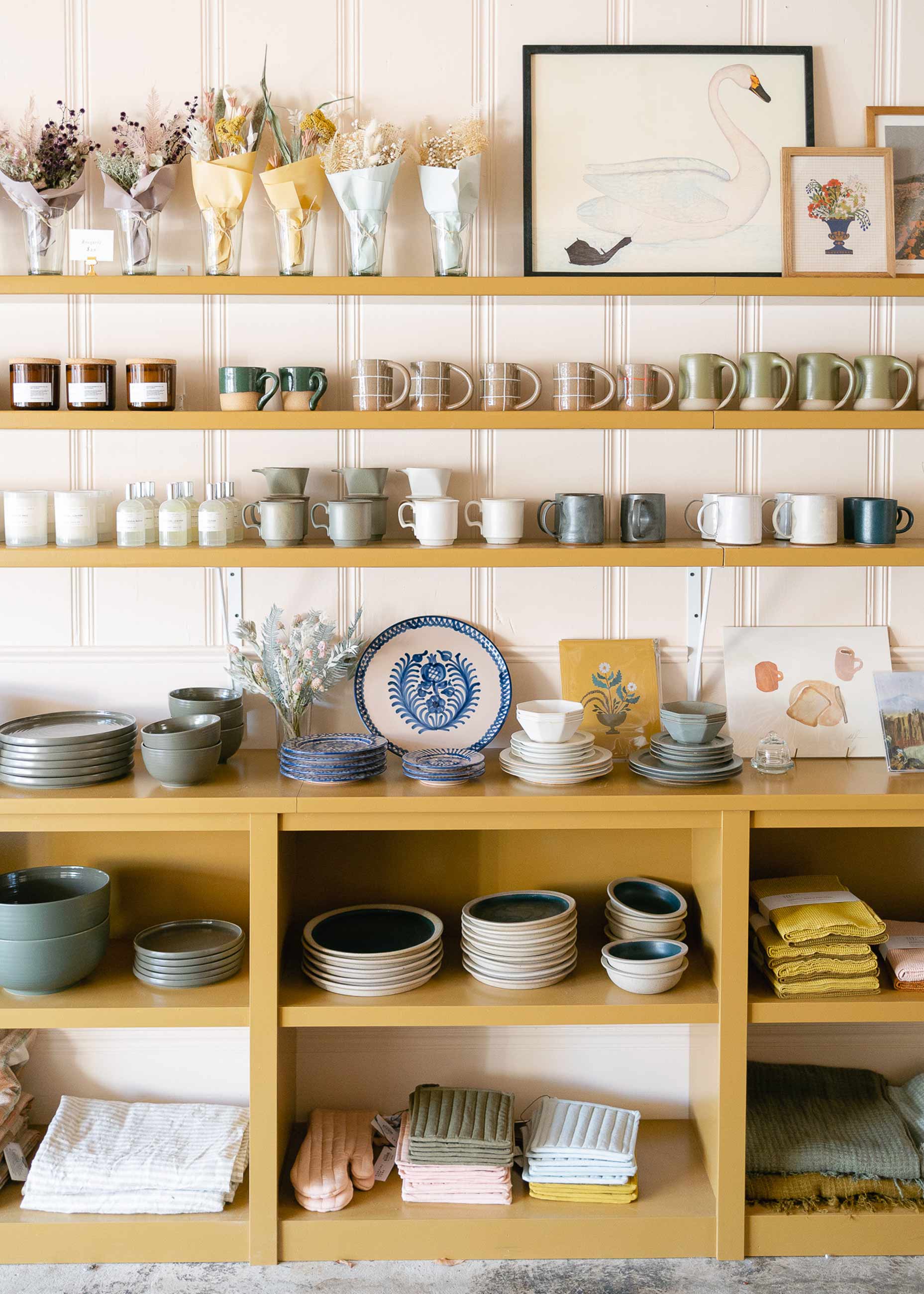 Items sitting on a mustard yellow shelf in general store. 