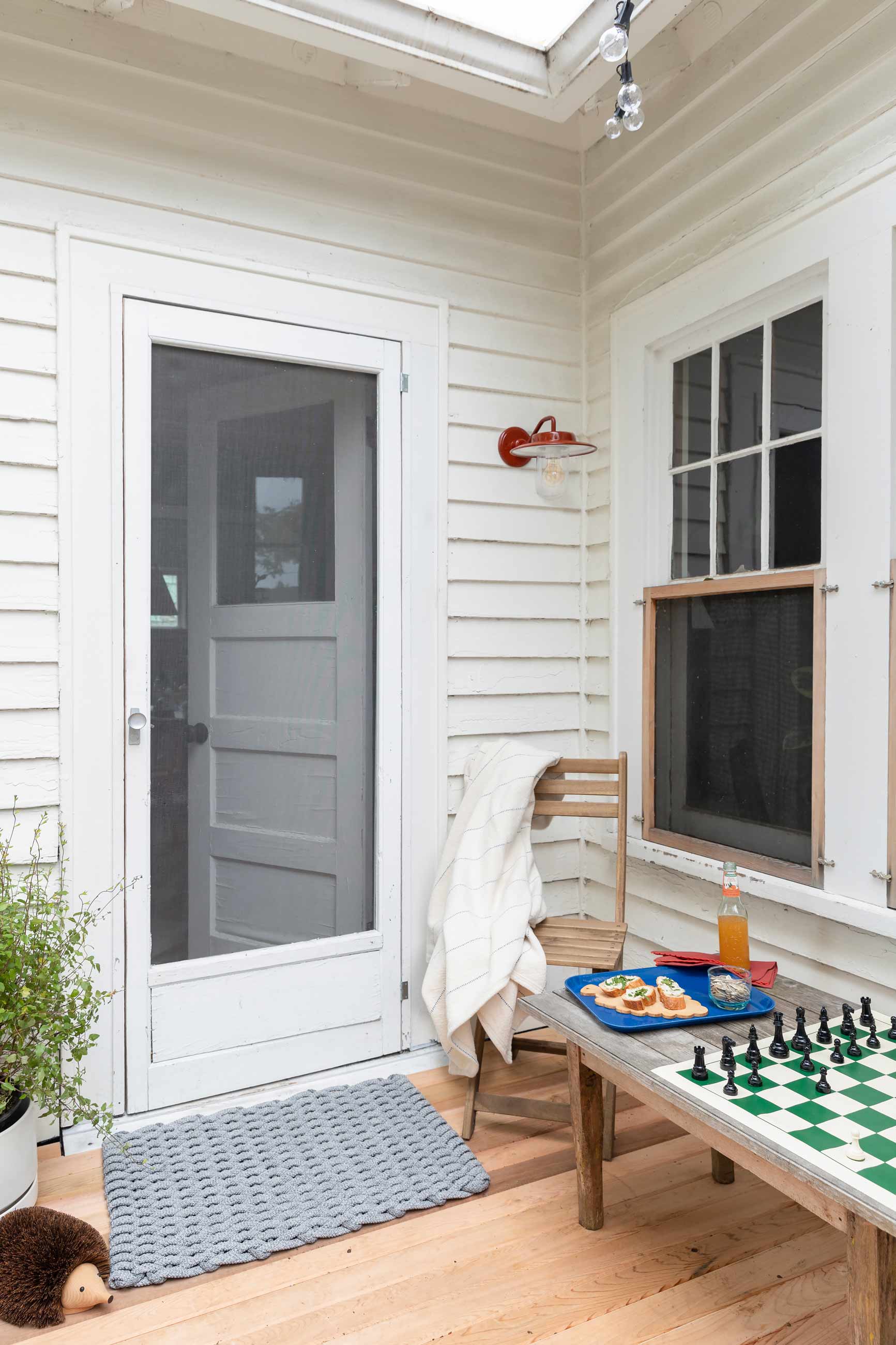 Side porch with chess board set up between two chairs. 