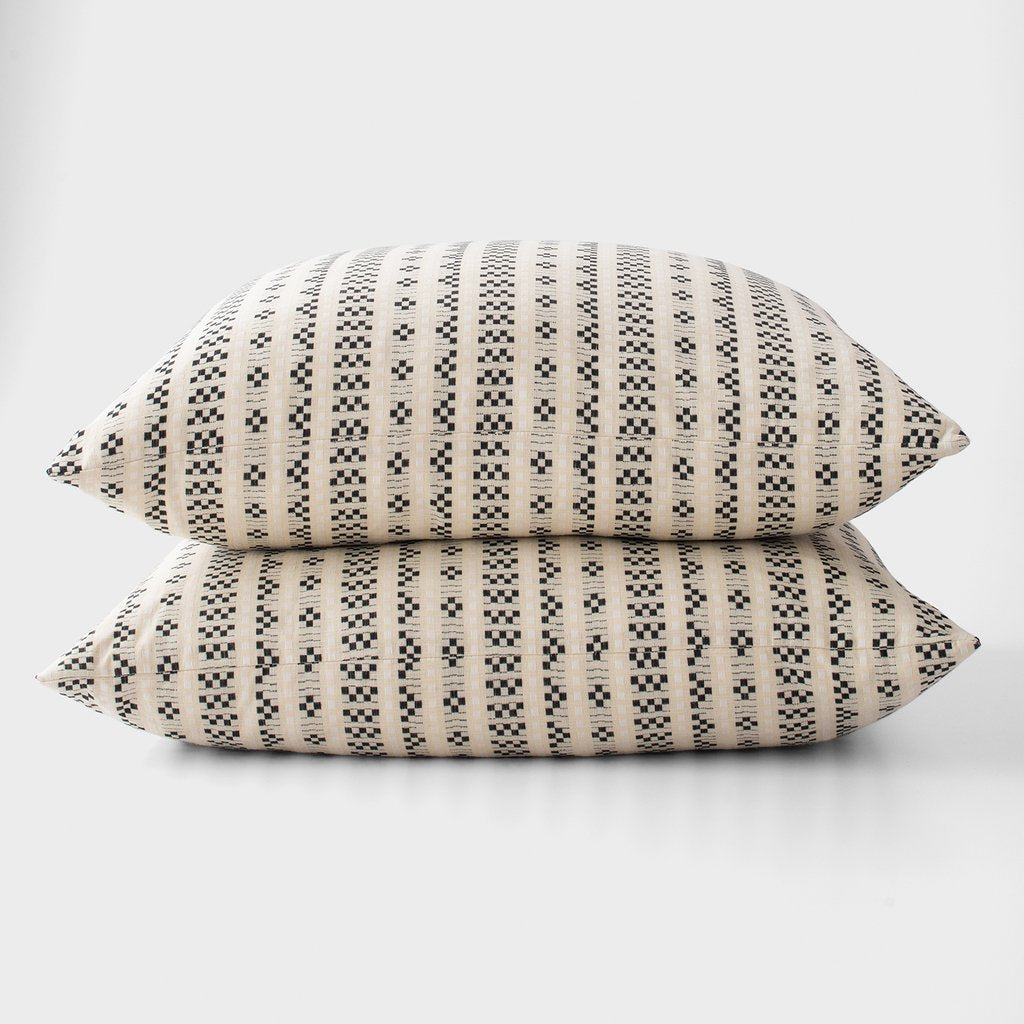 two black and white printed pillows stacked on top of each other