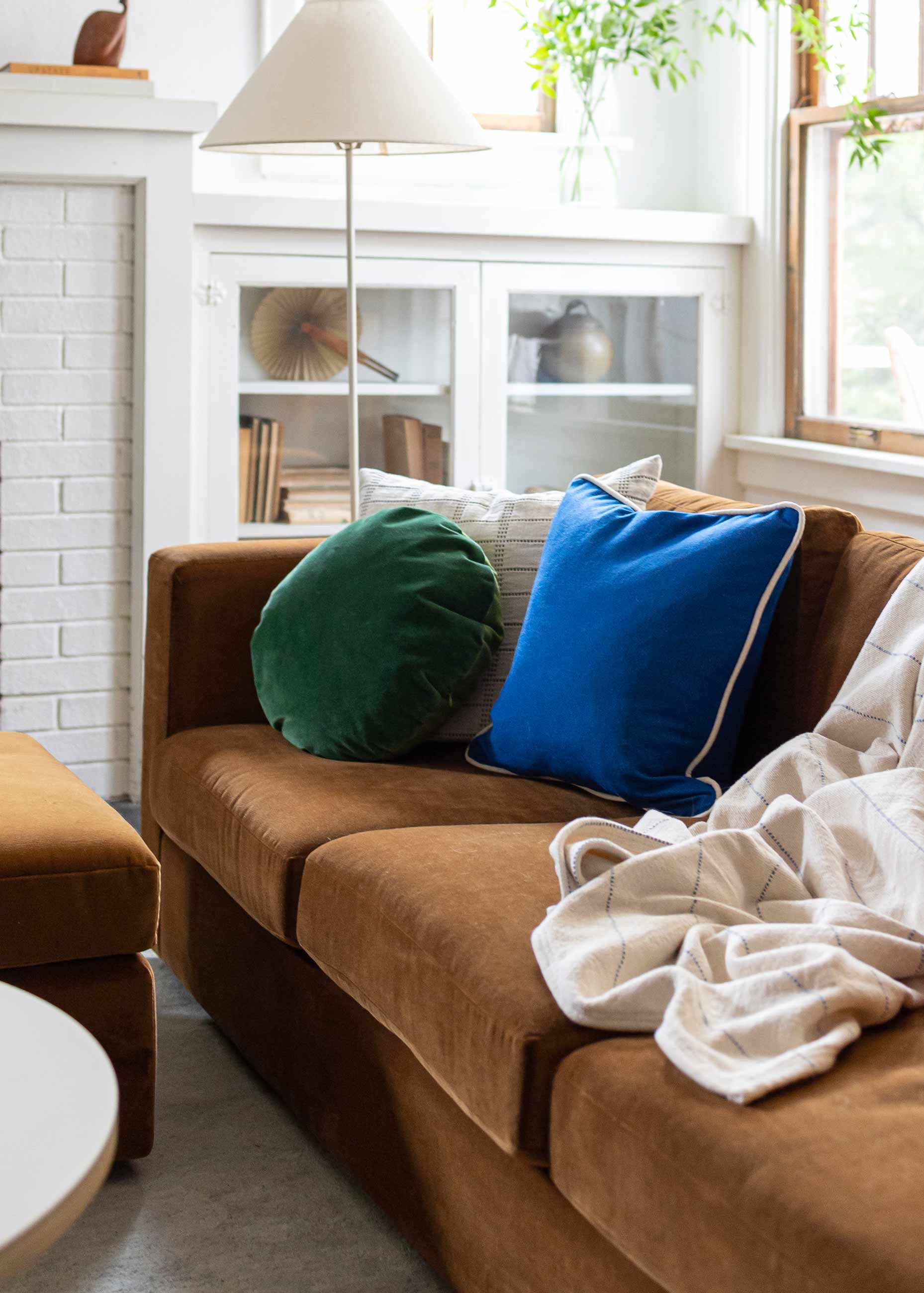 Toffee colored velvet couch with bright throw pillows.