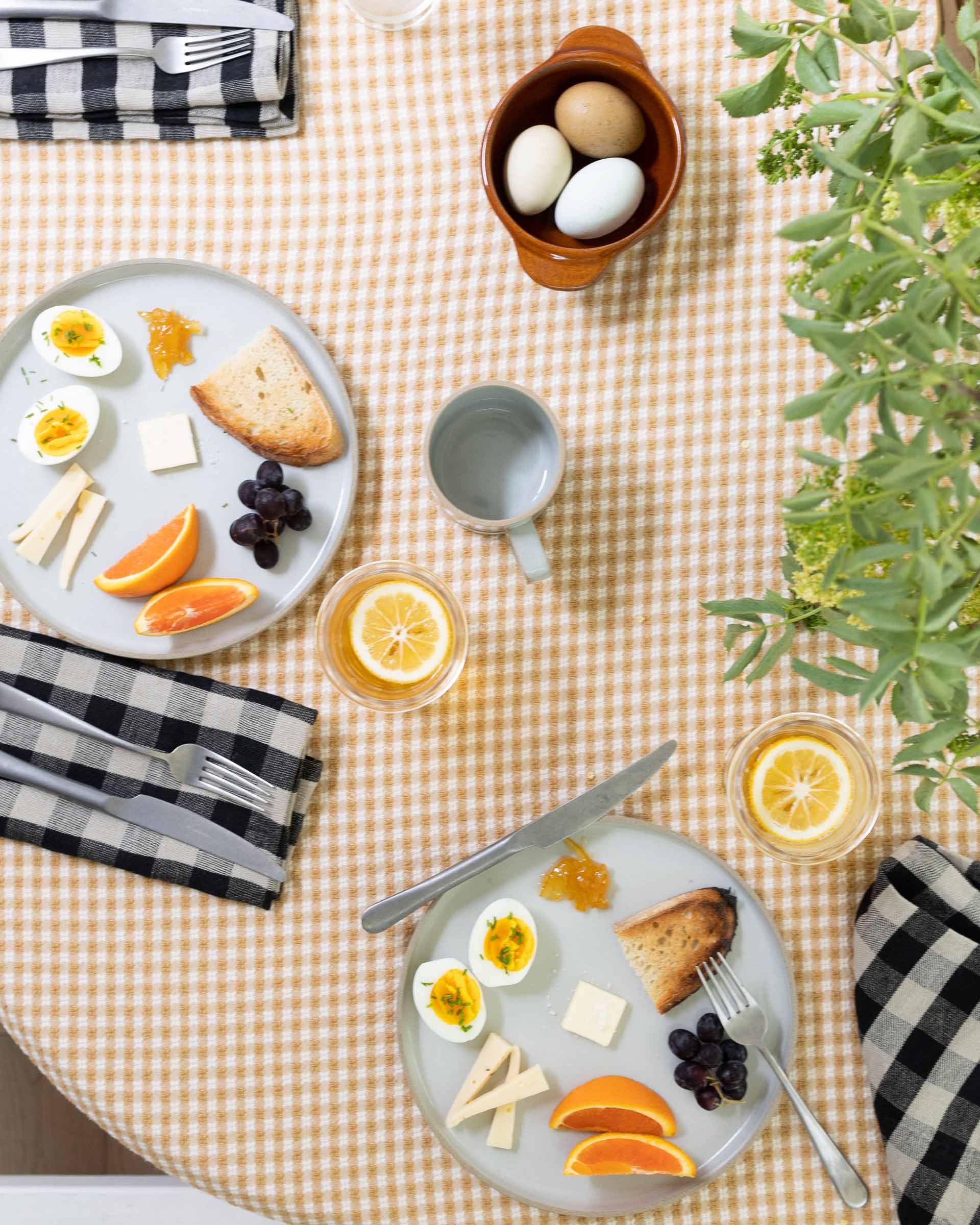 A summer table with plaid linen napkins and various glassware. 