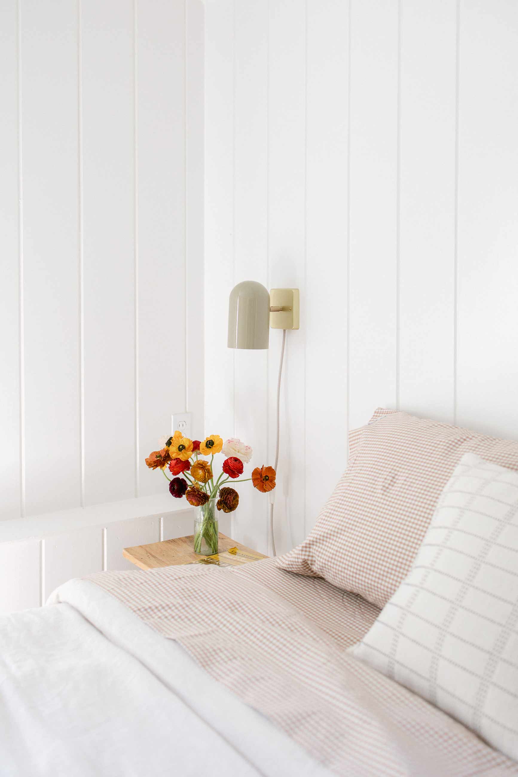 Sunny bedroom with fresh cut flowers on bedside table. 