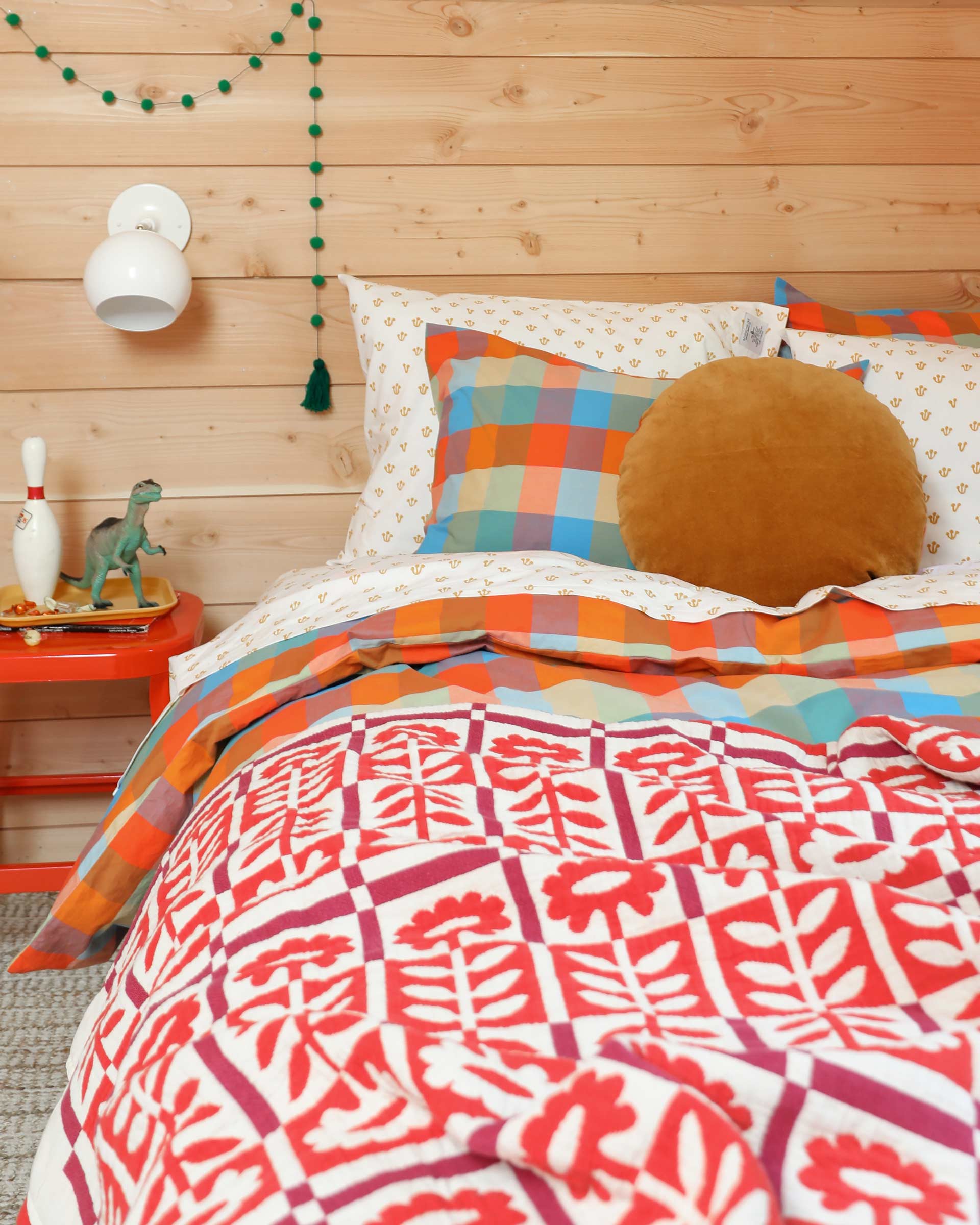 The Stillwater Quilt in Red with various heirloom bedding in a kid's bedroom of a modern cabin.