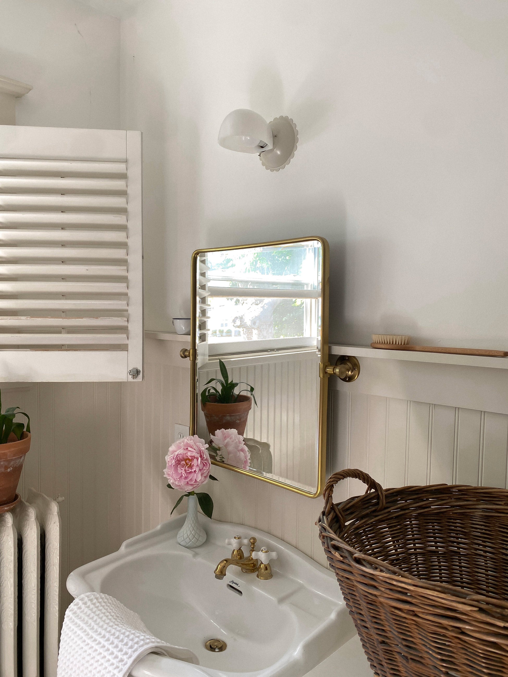 Traditional style bathroom with scalloped sconce above sink. 