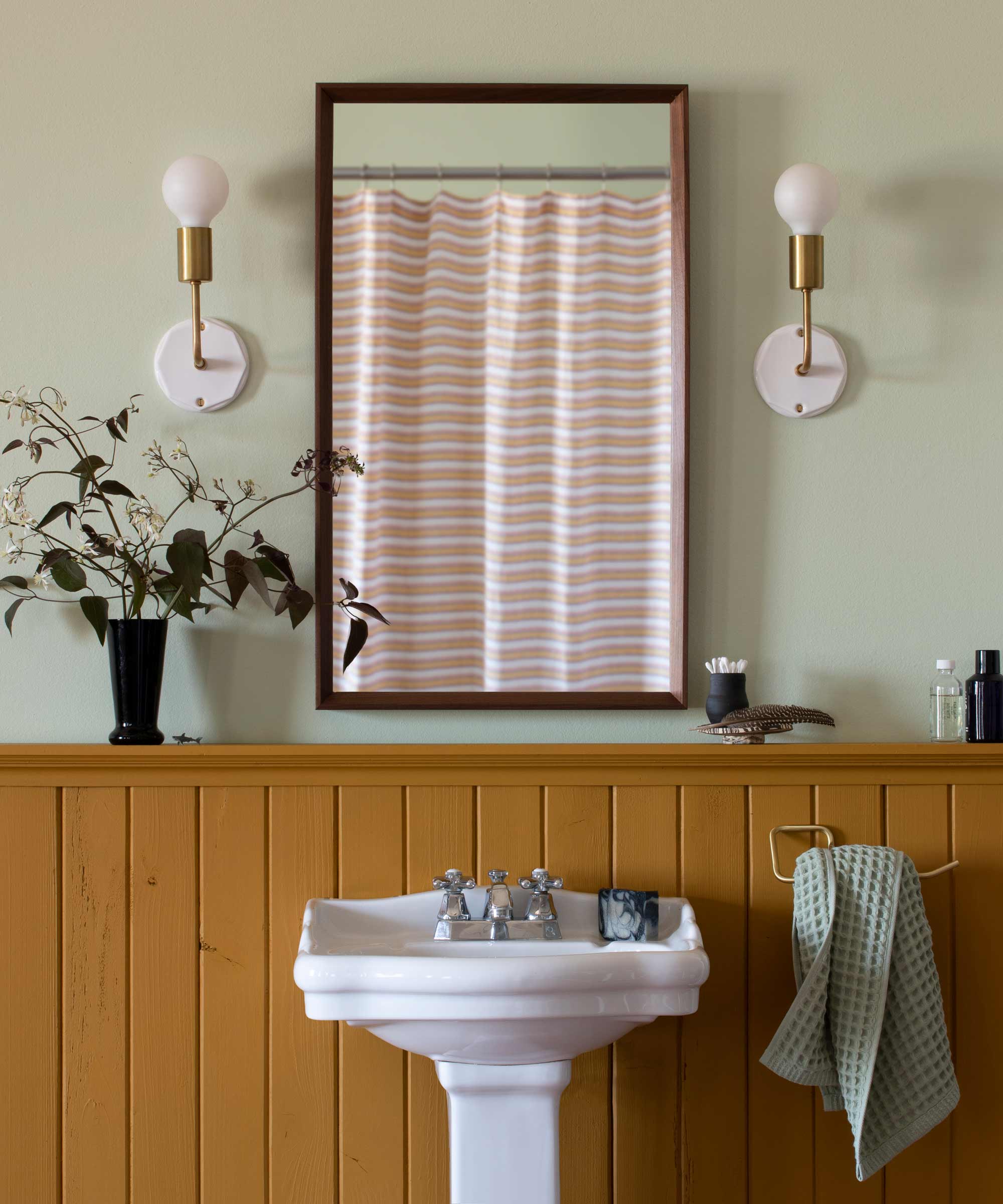 Wall sconces flanking a mirror in a small bathroom.