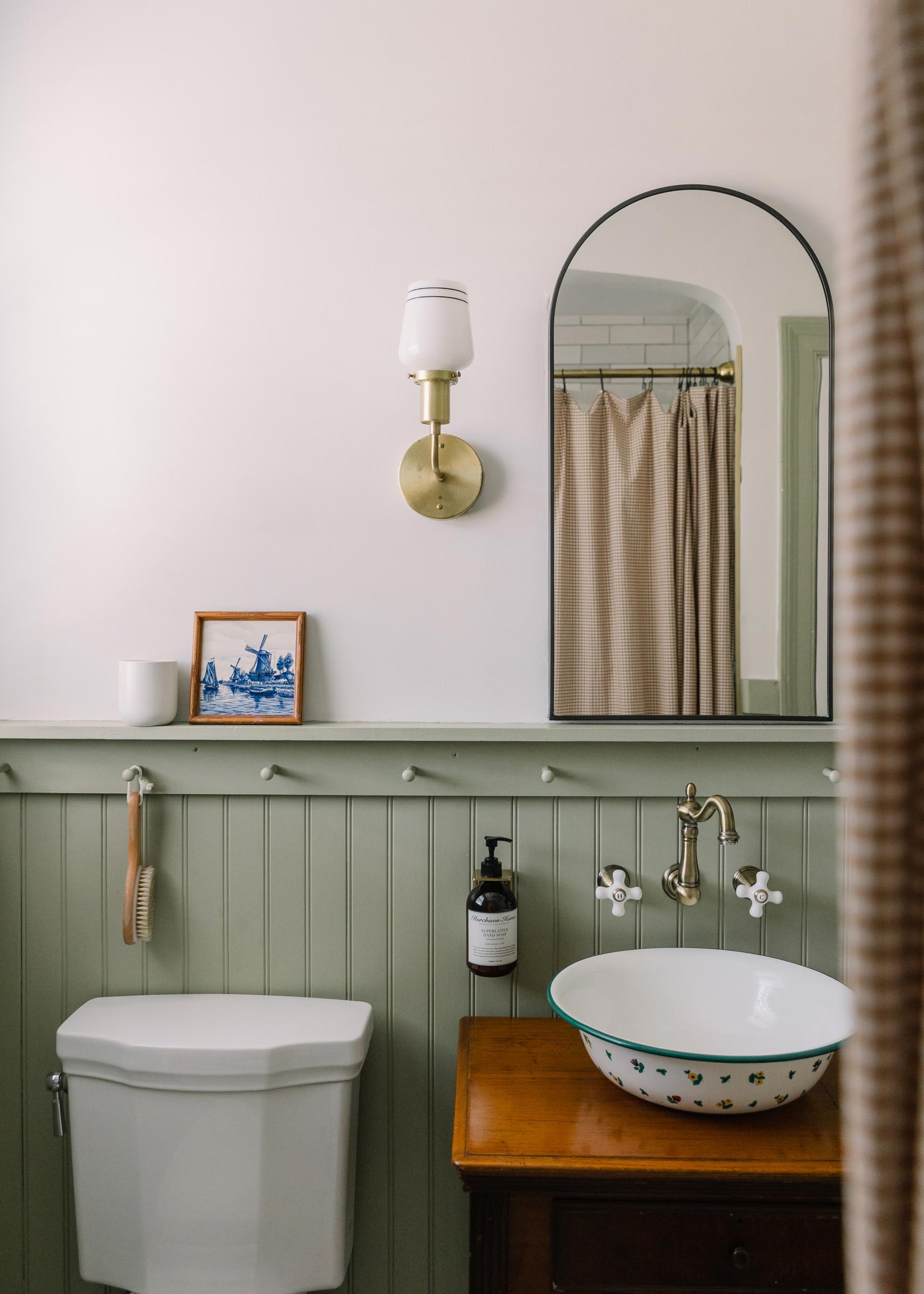 A brass wall sconce in a green bathroom. 