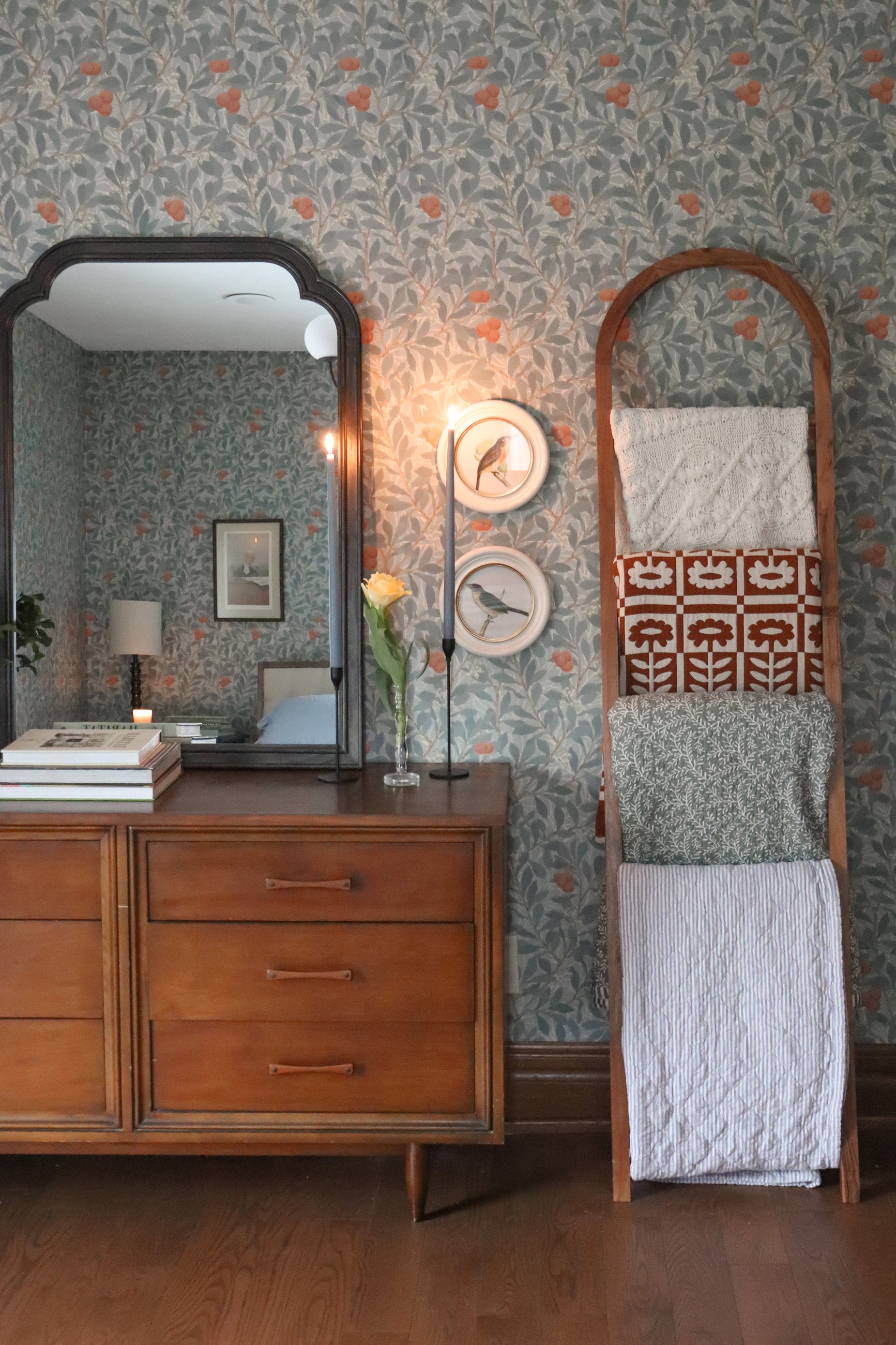 Wallpapered bedroom with dresser and blanket ladder.