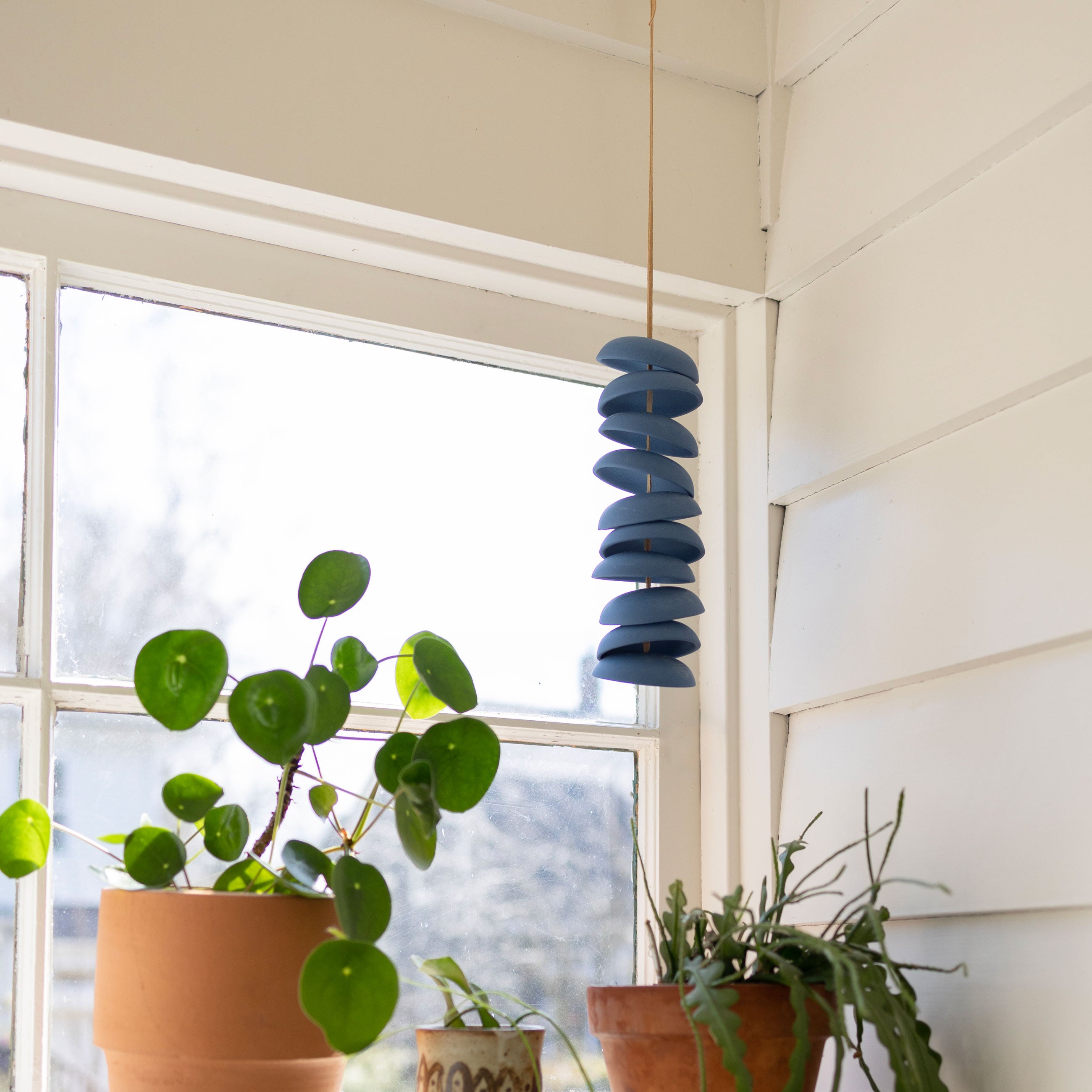 Wind-chime hanging above plants in terracotta planters. 