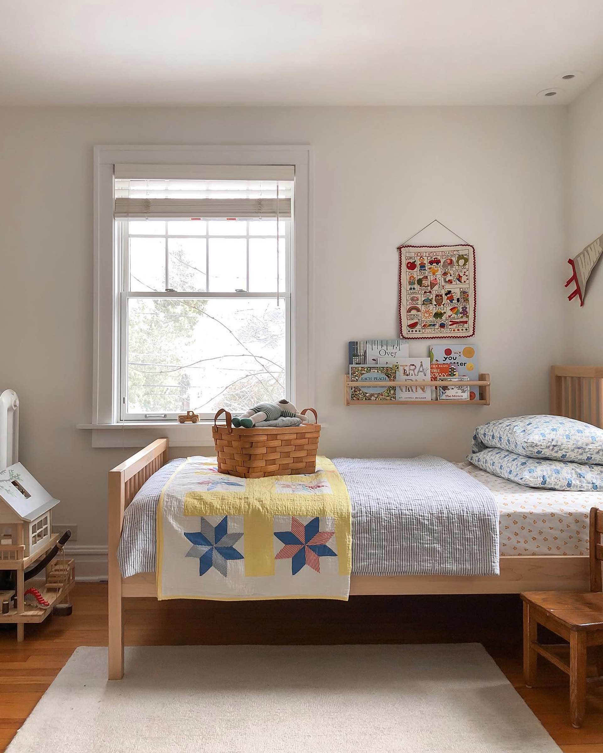 Wooden kid's bed with striped coverlet and vintage quilt.