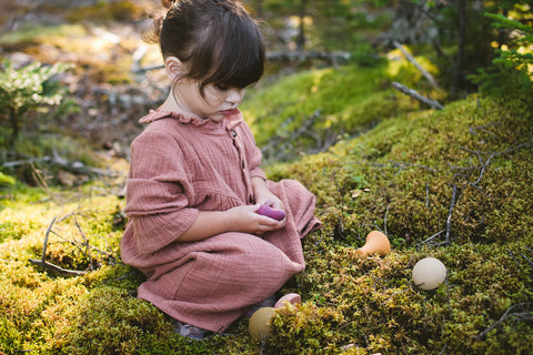 Girl playing with wooden mushrooms in mossy forest