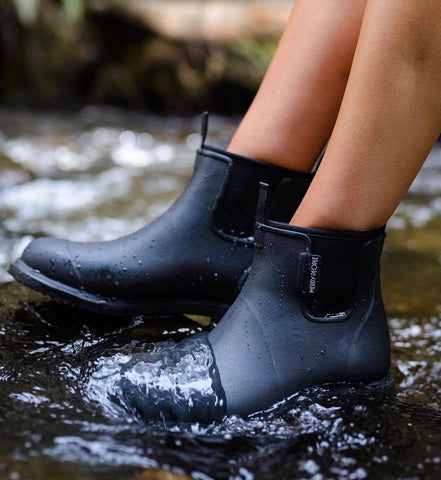 Person wearing Black Bobbi Gumboots by Merry People standing in water