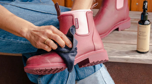 A person cleaning a pair of boots with a cloth