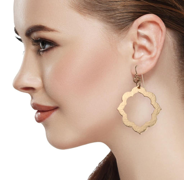 A woman wearing Pierced Hammered Bronze Arabesque Flower Earrings, adding elegance and style to her appearance