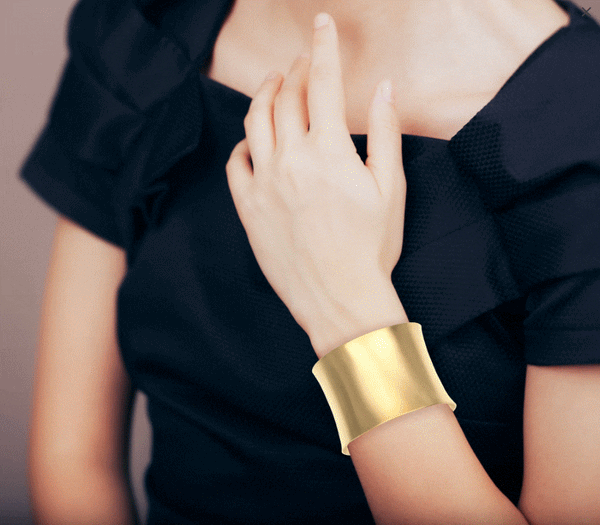 A woman showcasing a stylish Brushed Anticlastic Bronze Cuff Bracelet, adding a touch of elegance to her ensemble