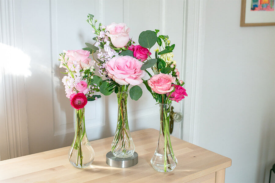 Pink roses in three clear glass vases arranged together