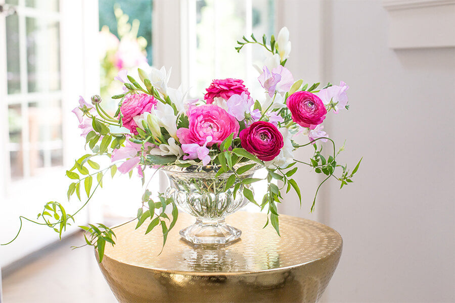 Bright pink flowers in a wide clear compote vase